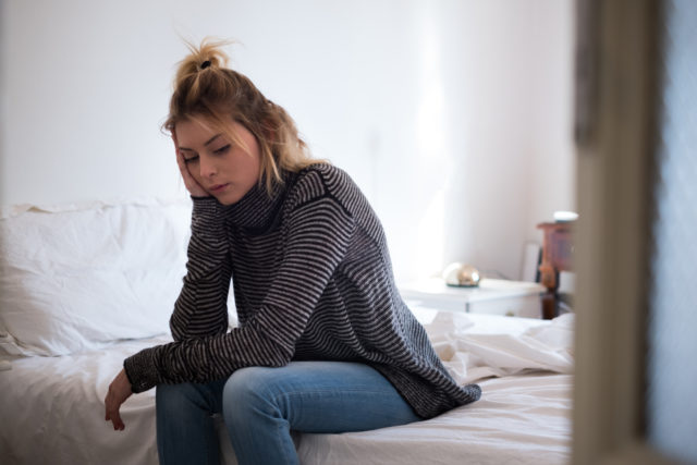 Sad young tired woman sitting on the bed