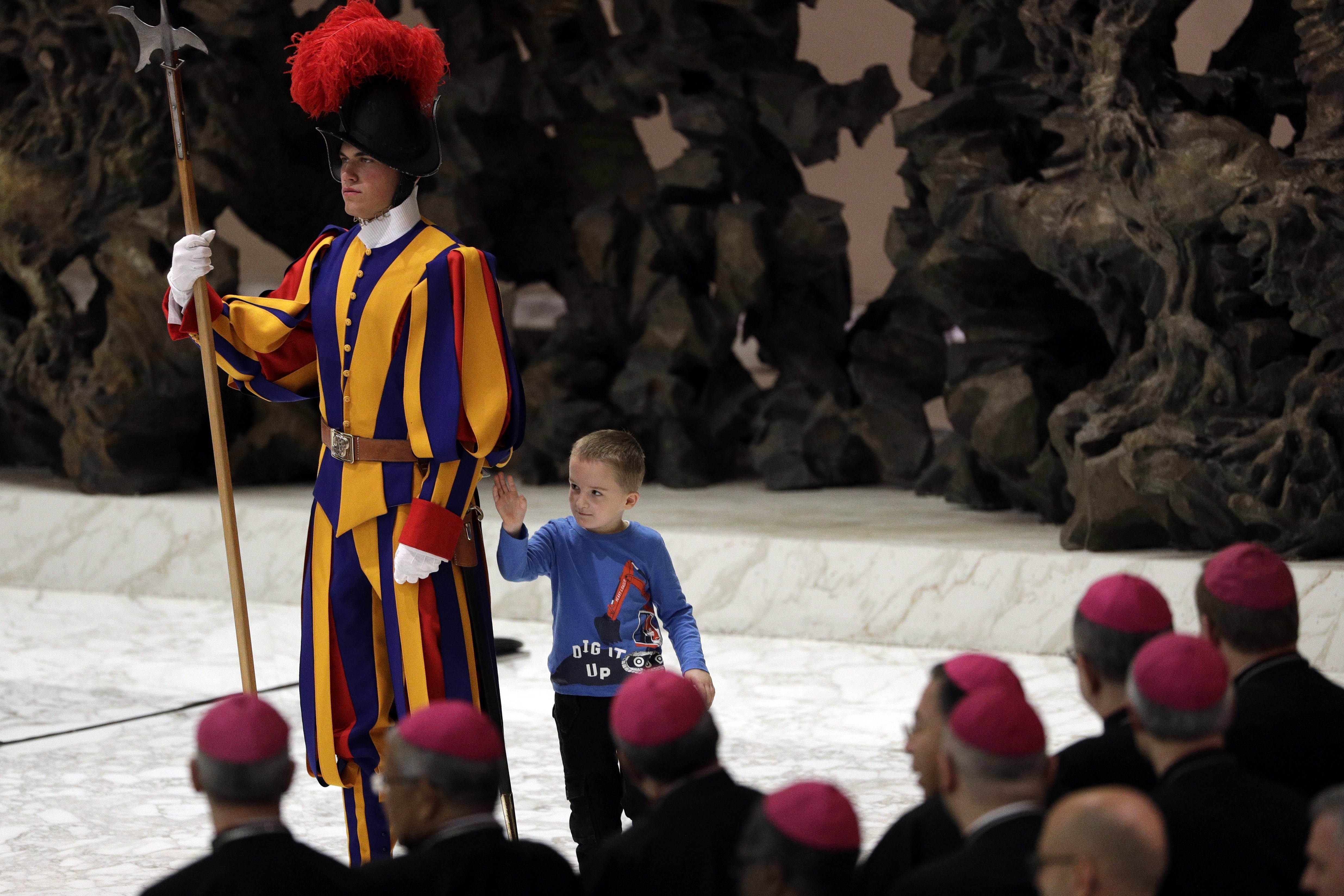 The child walks around the back of the guard