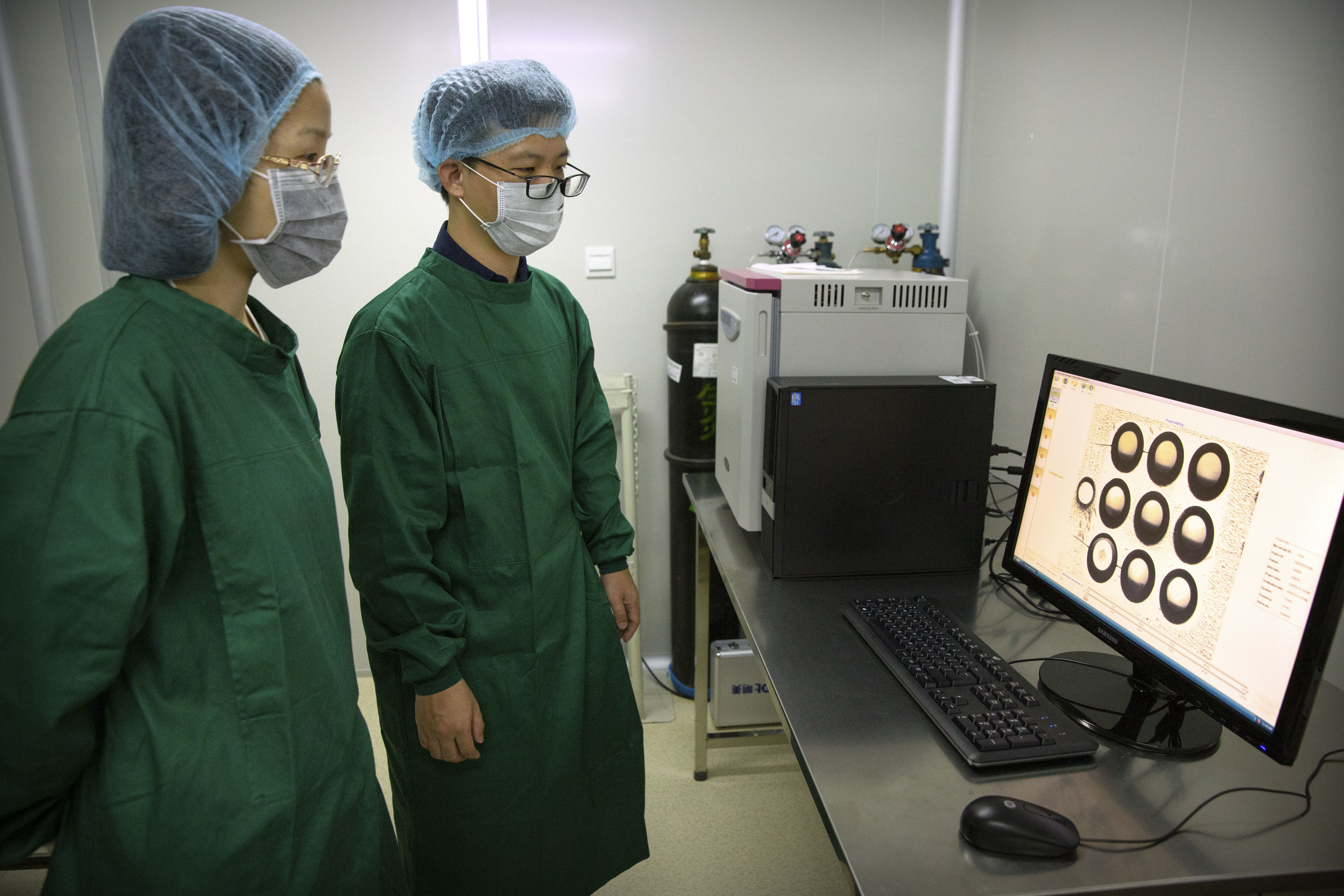 Zhou Xiaoqin, left, and Qin Jinzhou, an embryologist, who were part of the team working with scientist He Jiankui, view a time lapse image of embryos on a computer screen at a lab in Shenzhen