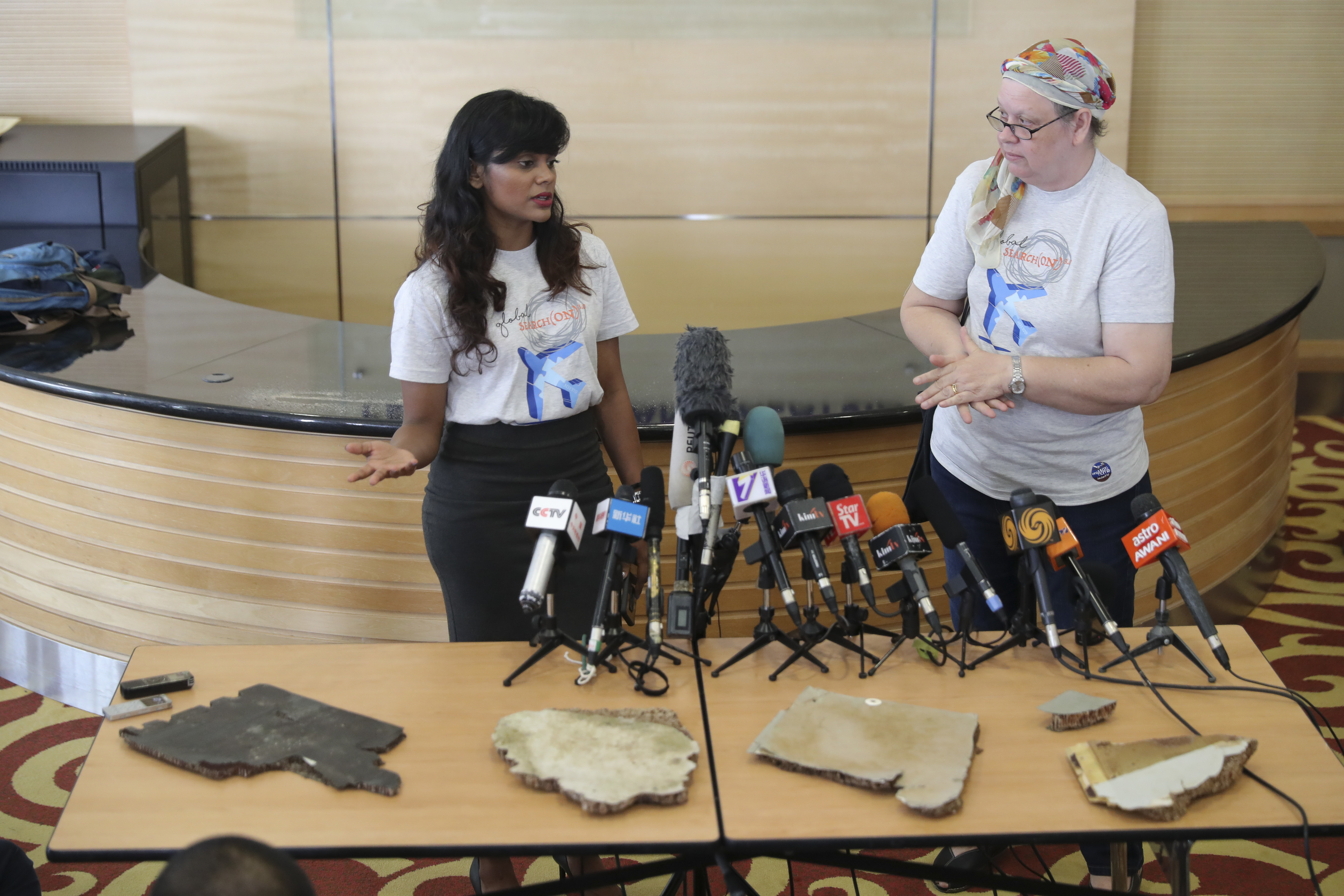 Grace Nathan, left, whose mother was on Malaysia Airlines Flight 370, and Jacquita Gomes, right, wife of Patrick Gomes, the in-flight supervisor on the ill-fated plane, show pieces of debris believed to be from the missing plane at the Ministry of Transport in Putrajaya