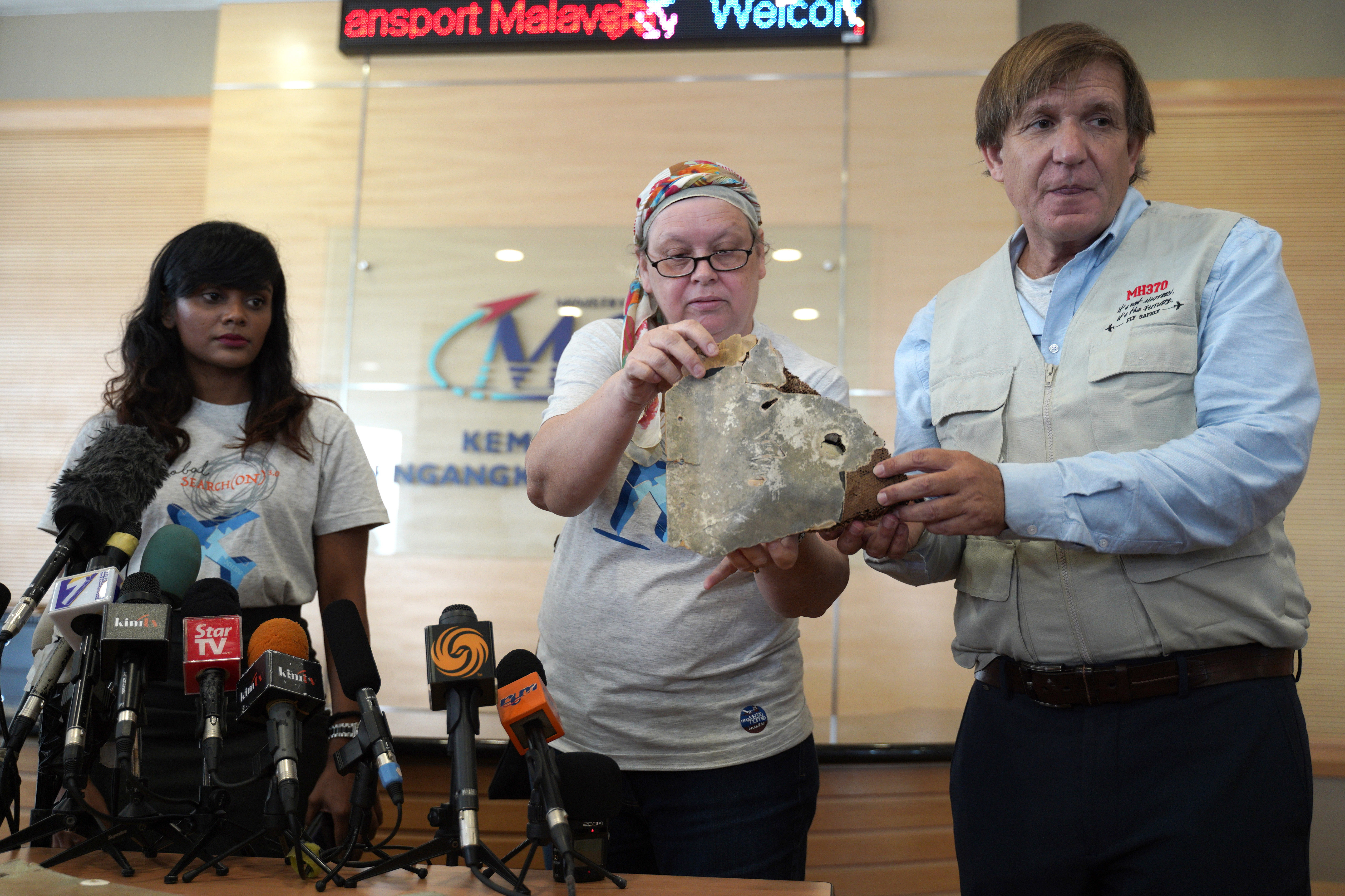 Jacquita Gomes, centre, wife of Patrick Gomes, the in-flight supervisor on the ill-fated Malaysia Airlines Flight 370, and Blaine Alan Gibson, right, a representative of the next of kin of MH370, show a piece of debris believed to be from missing plane MH370 at the Ministry of Transport in Putrajaya, Malaysia