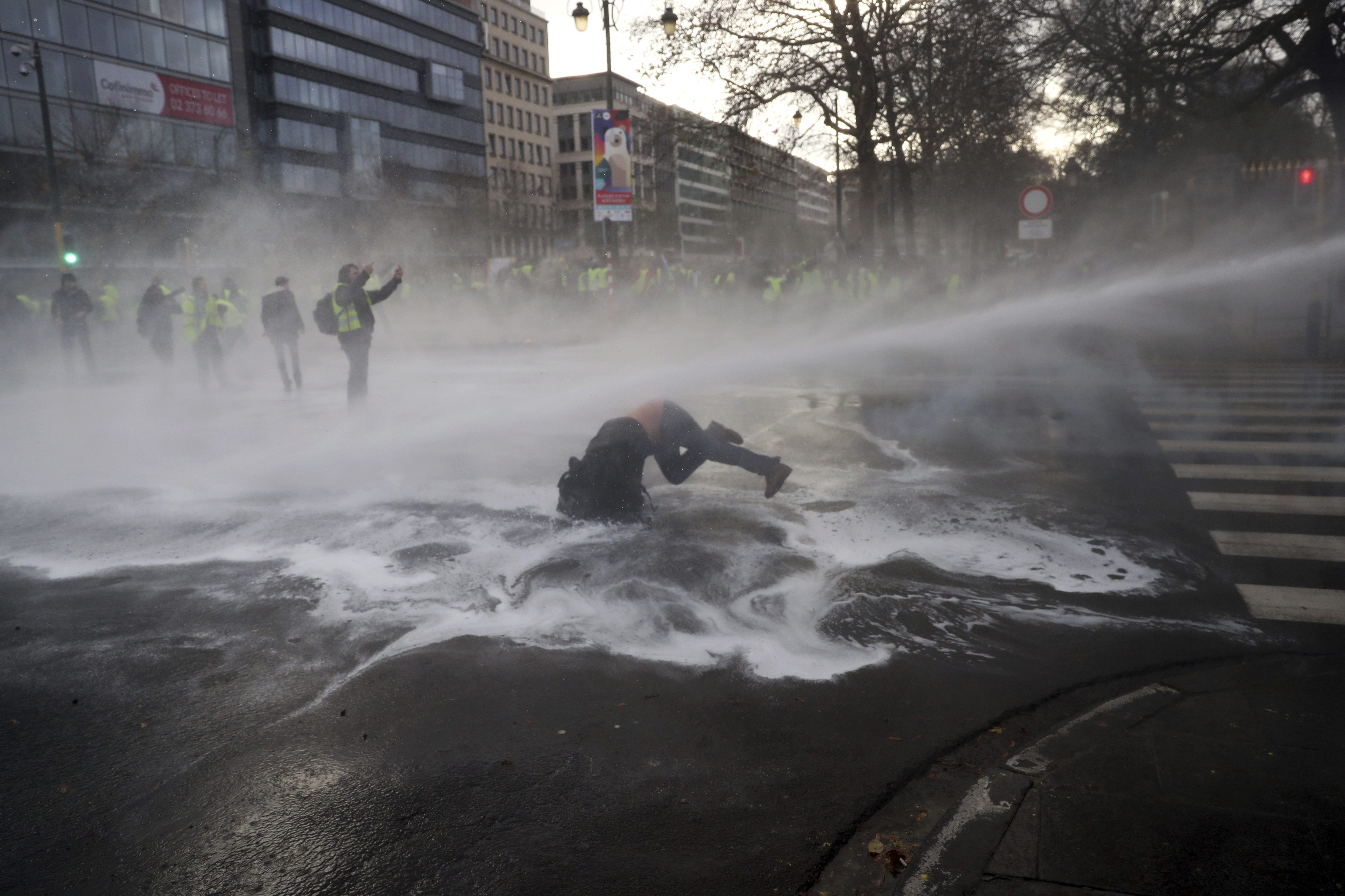 A demonstrator gets hit by a water cannon during a protest of the 'yellow jackets' in Brussels 