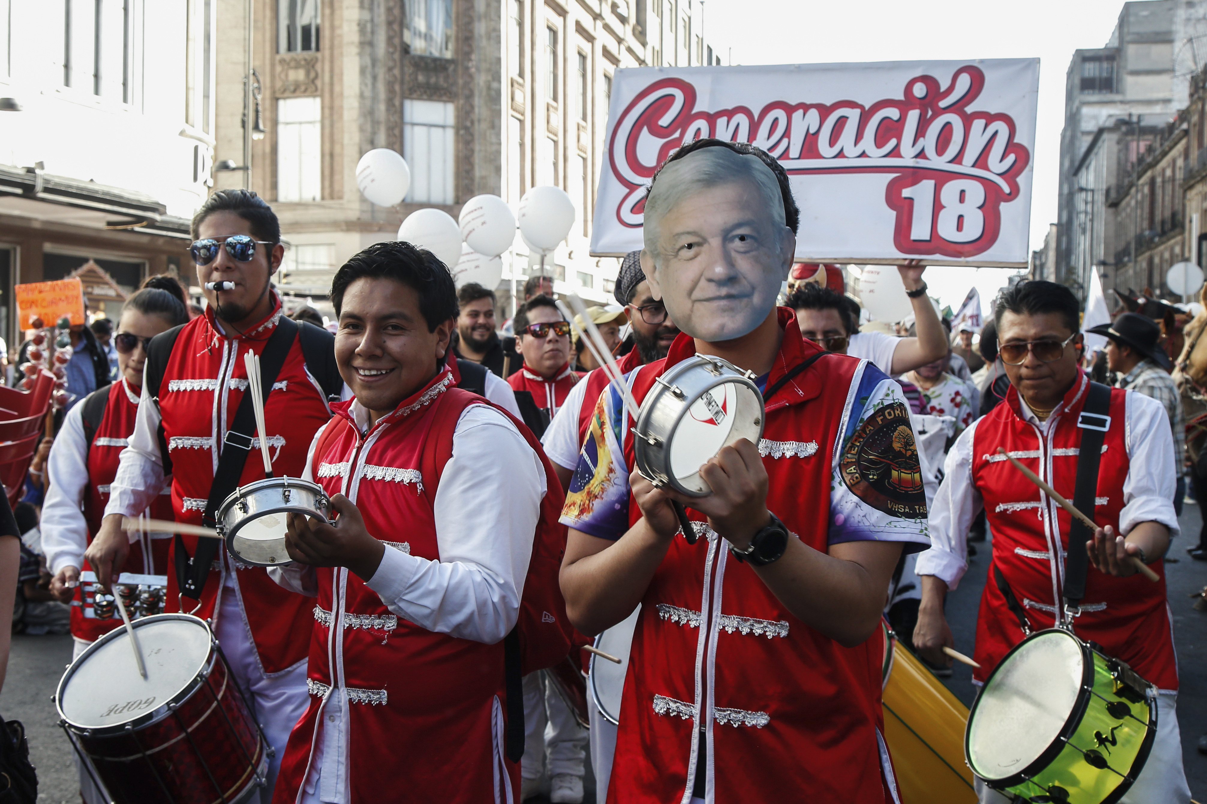 A musician wearing a mask depicting Mexico's new president Andres Manuel Lopez Obrador, taps a drum during inaugural festivities in Mexico City