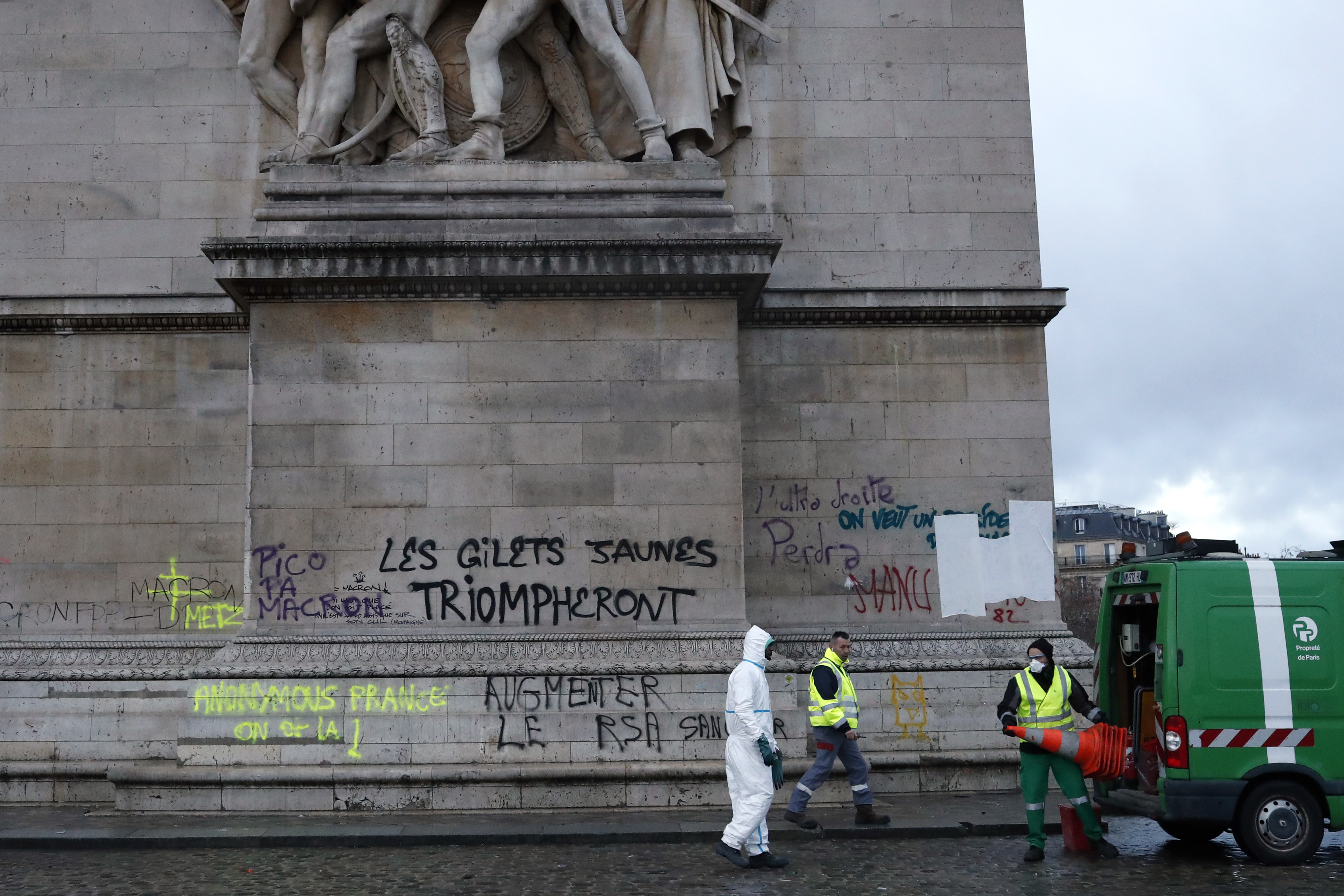 Workers prepare to clean graffiti reading 'yellow jackets will triumph' on the Arc de Triomphe in Paris