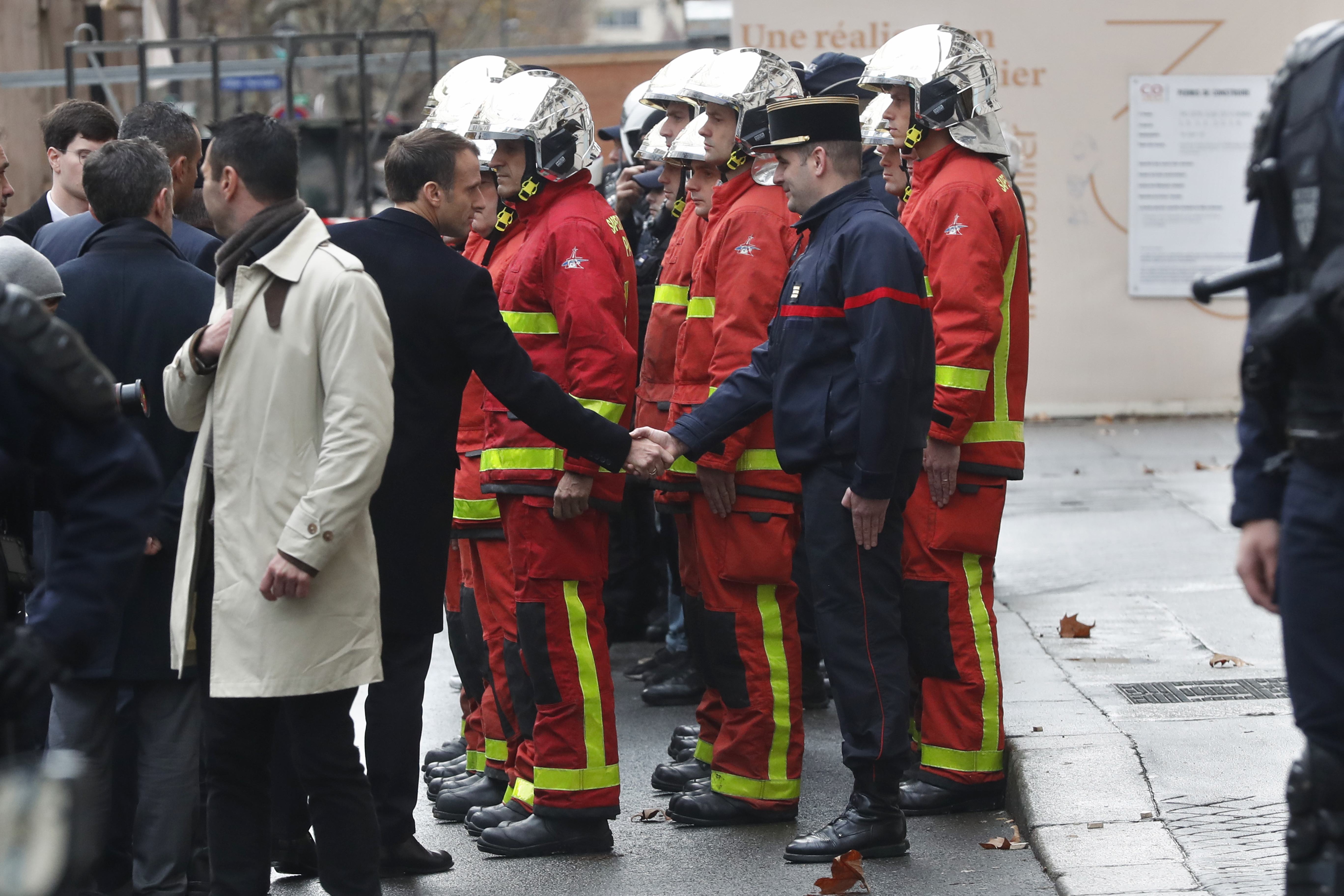 Emmanuel Macron shakes hands with a firefighter 