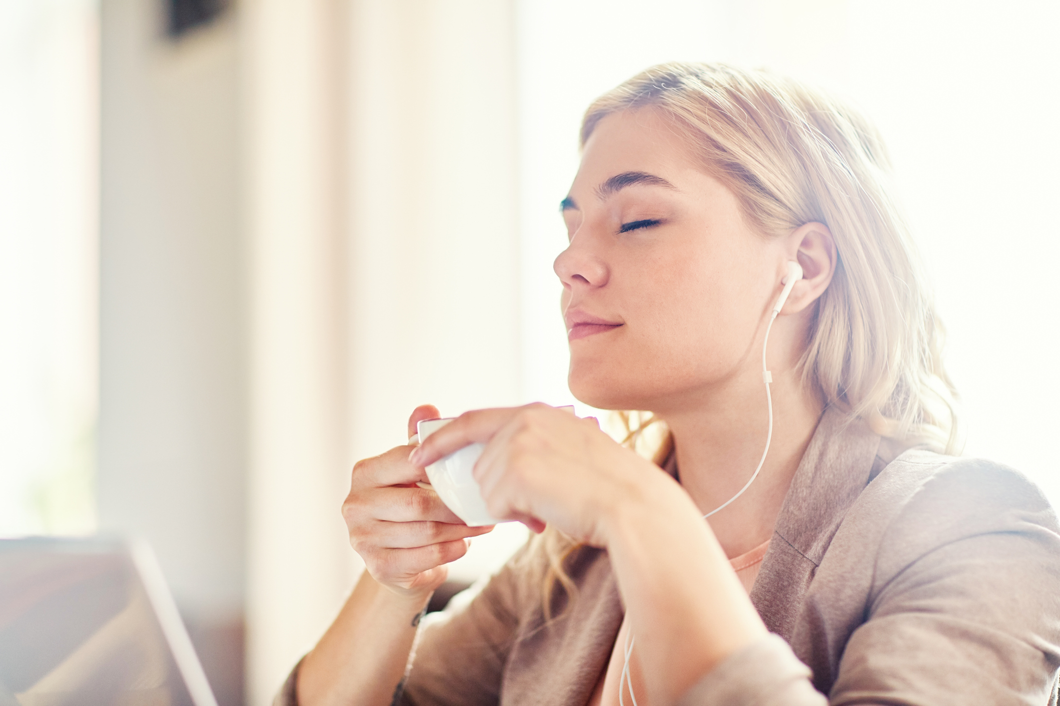 Serene girl with cup of tea listening to her favorite relaxing music at leisure