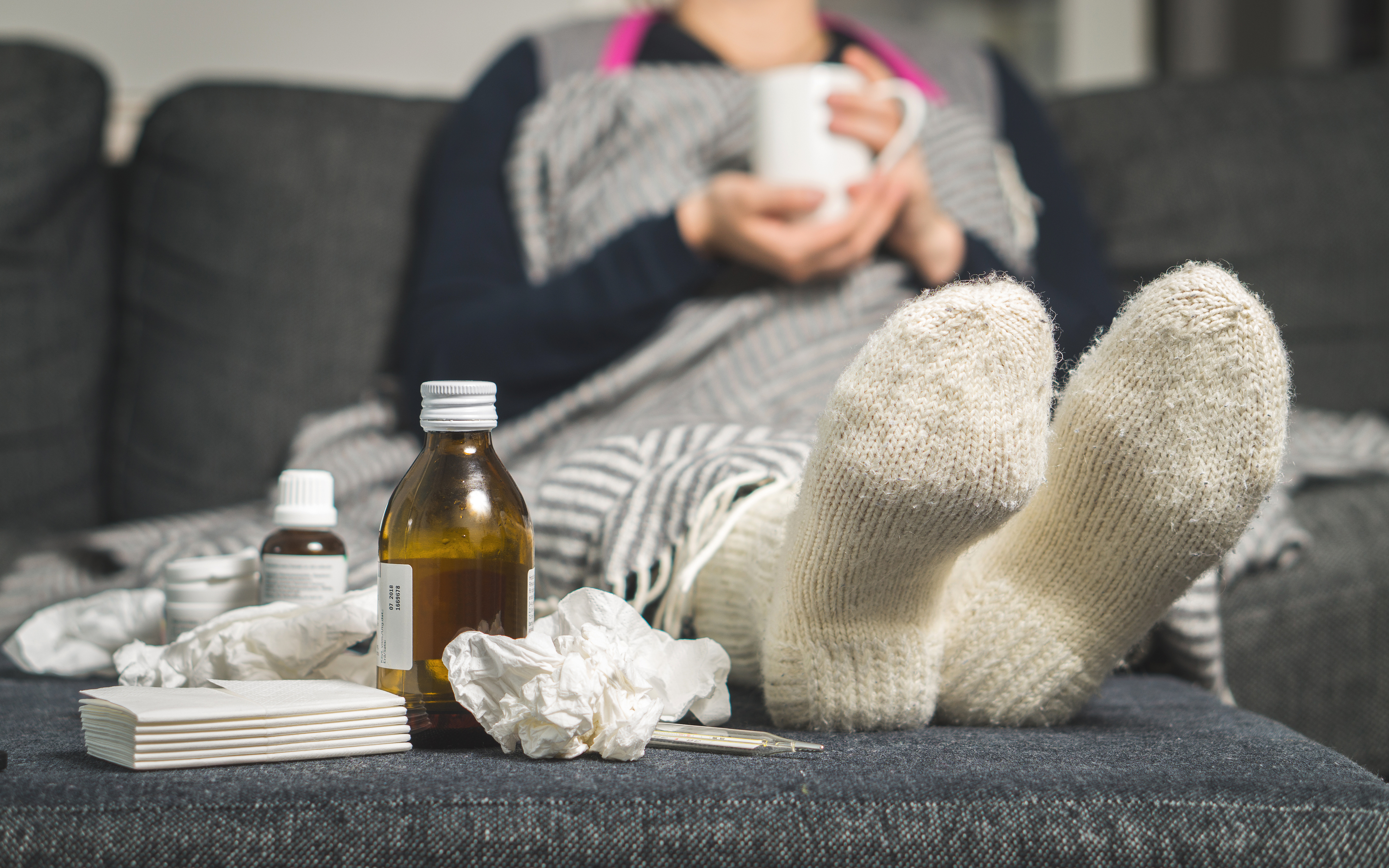 Person on sofa with cold medicine