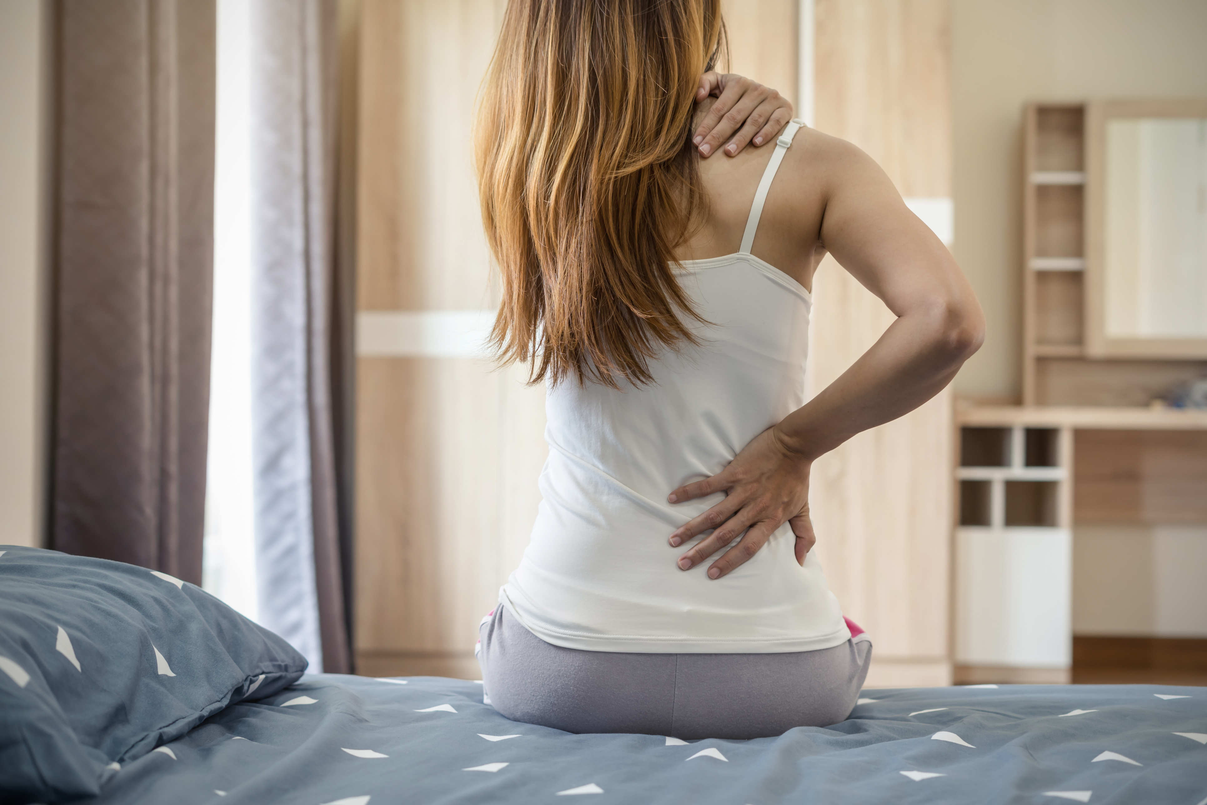 Woman suffering from back ache on the bed