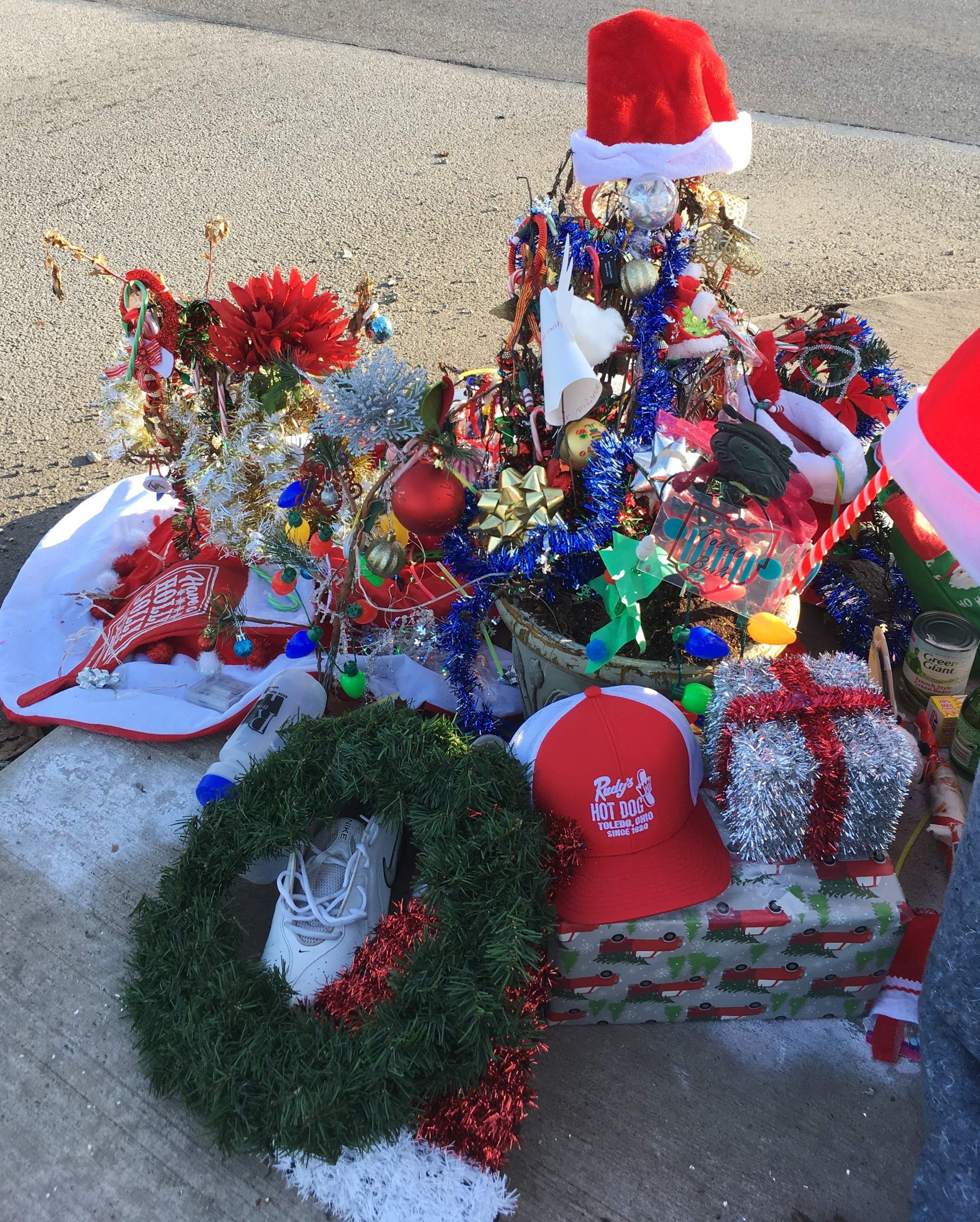 Christmas decorations and donations surround what is now known as the Christmas weed in Toledo, Ohio