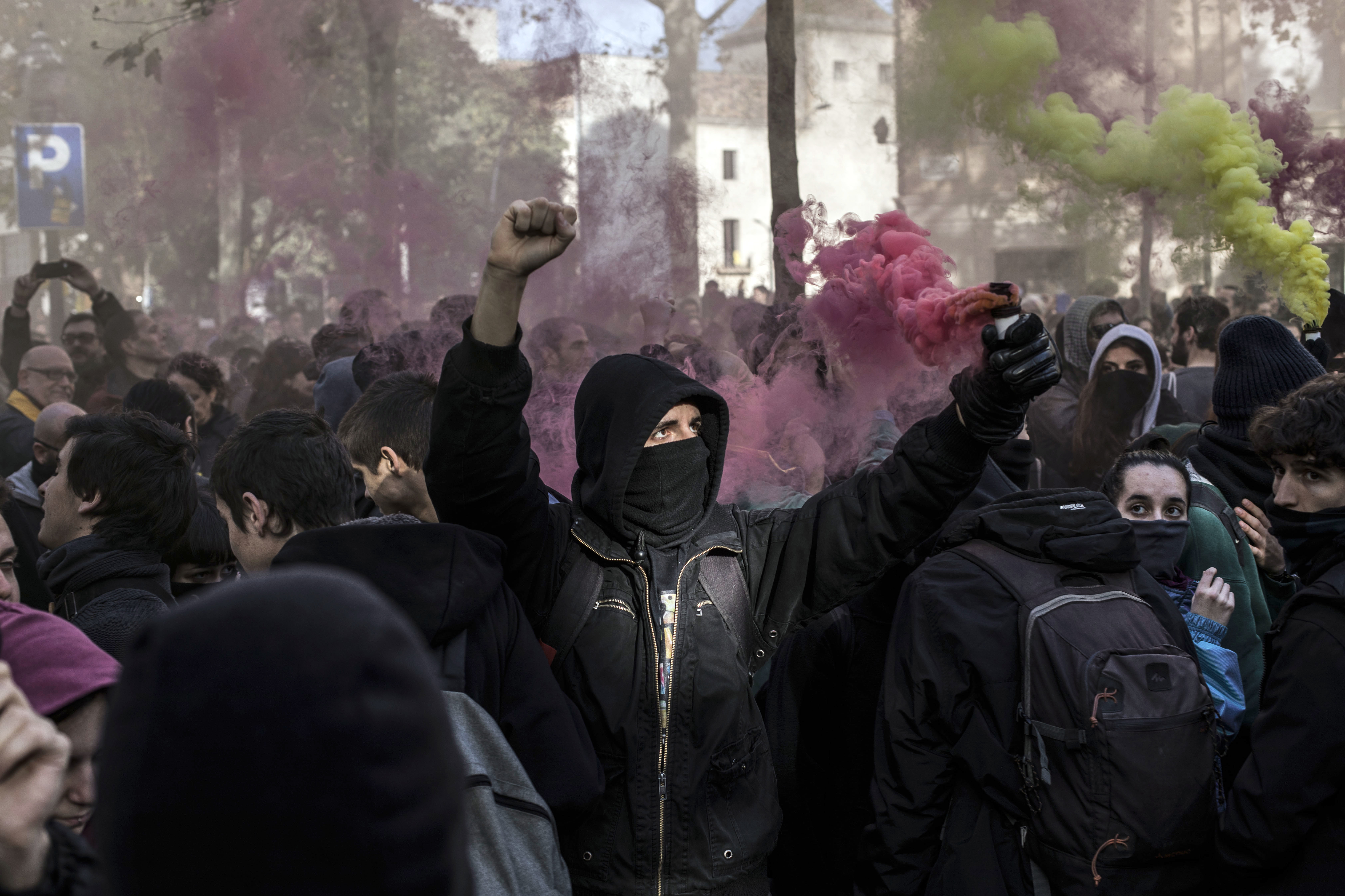 A masked protester holds up a smoke flare during clashes with riot police in Barcelona