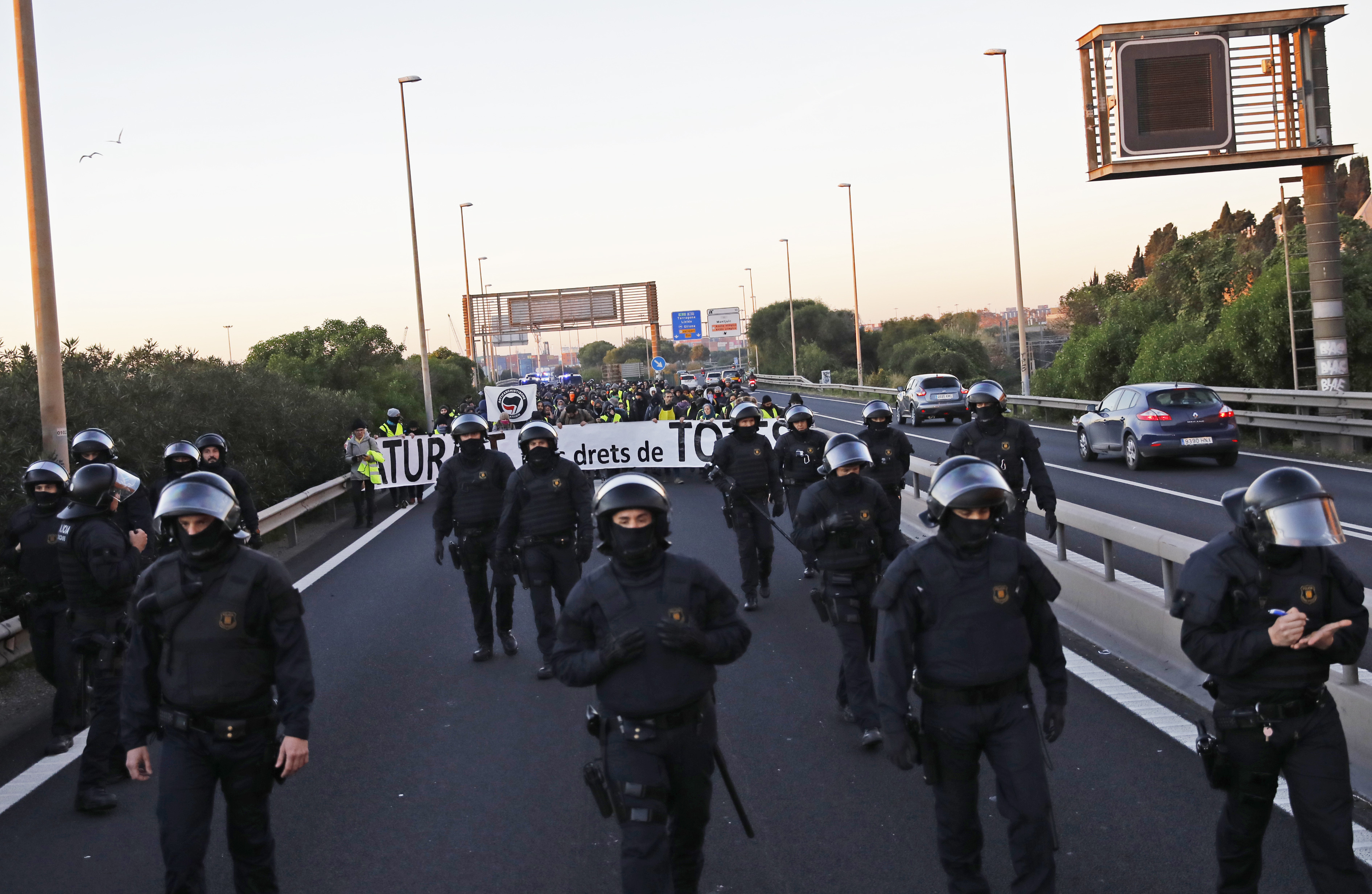 Catalan riot police escort pro-independence demonstrators as they march in protest in one of the city's access highway in Barcelona