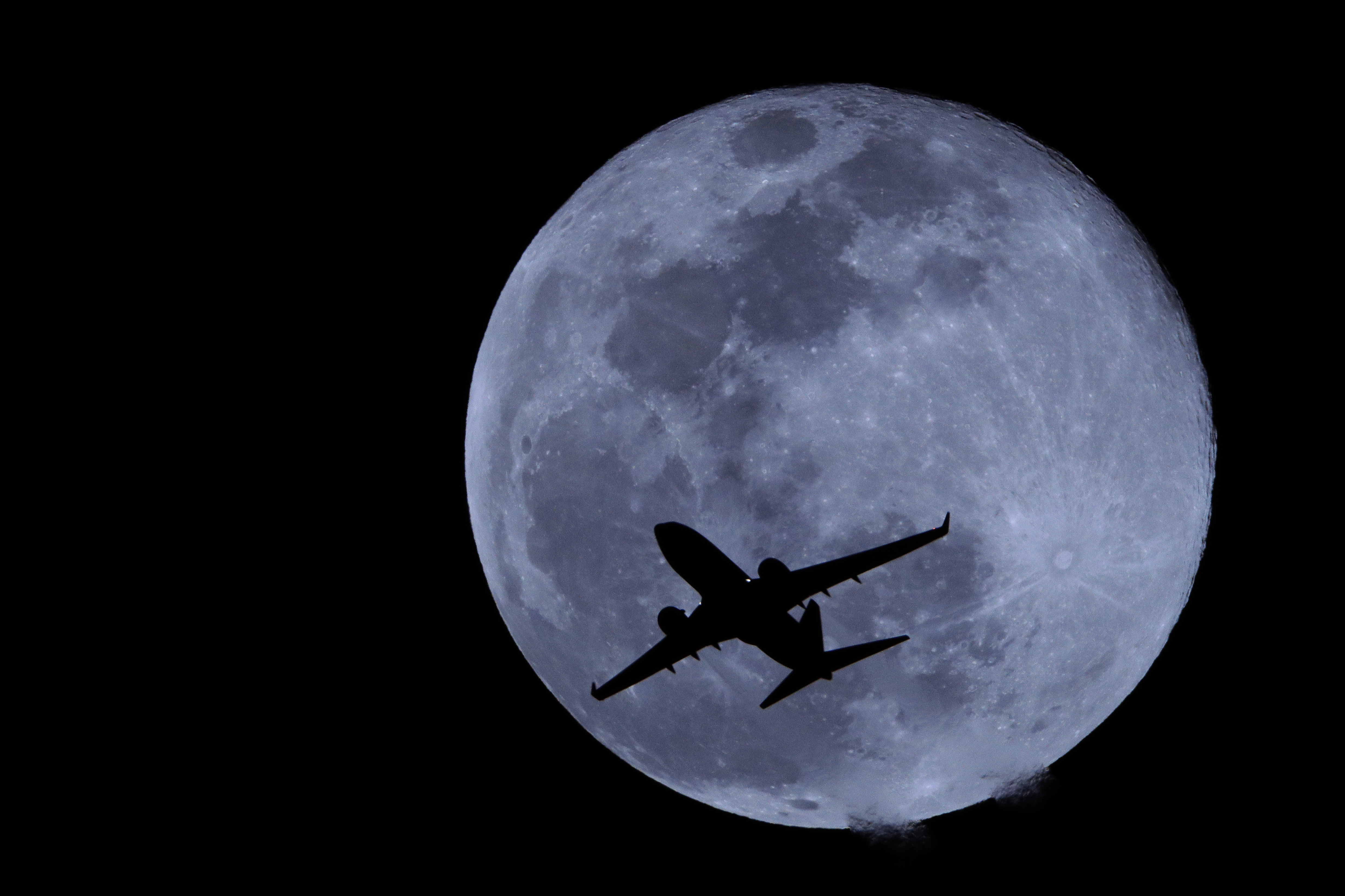 A passenger jet is silhouetted against the full moon in Phoenix, Arizona