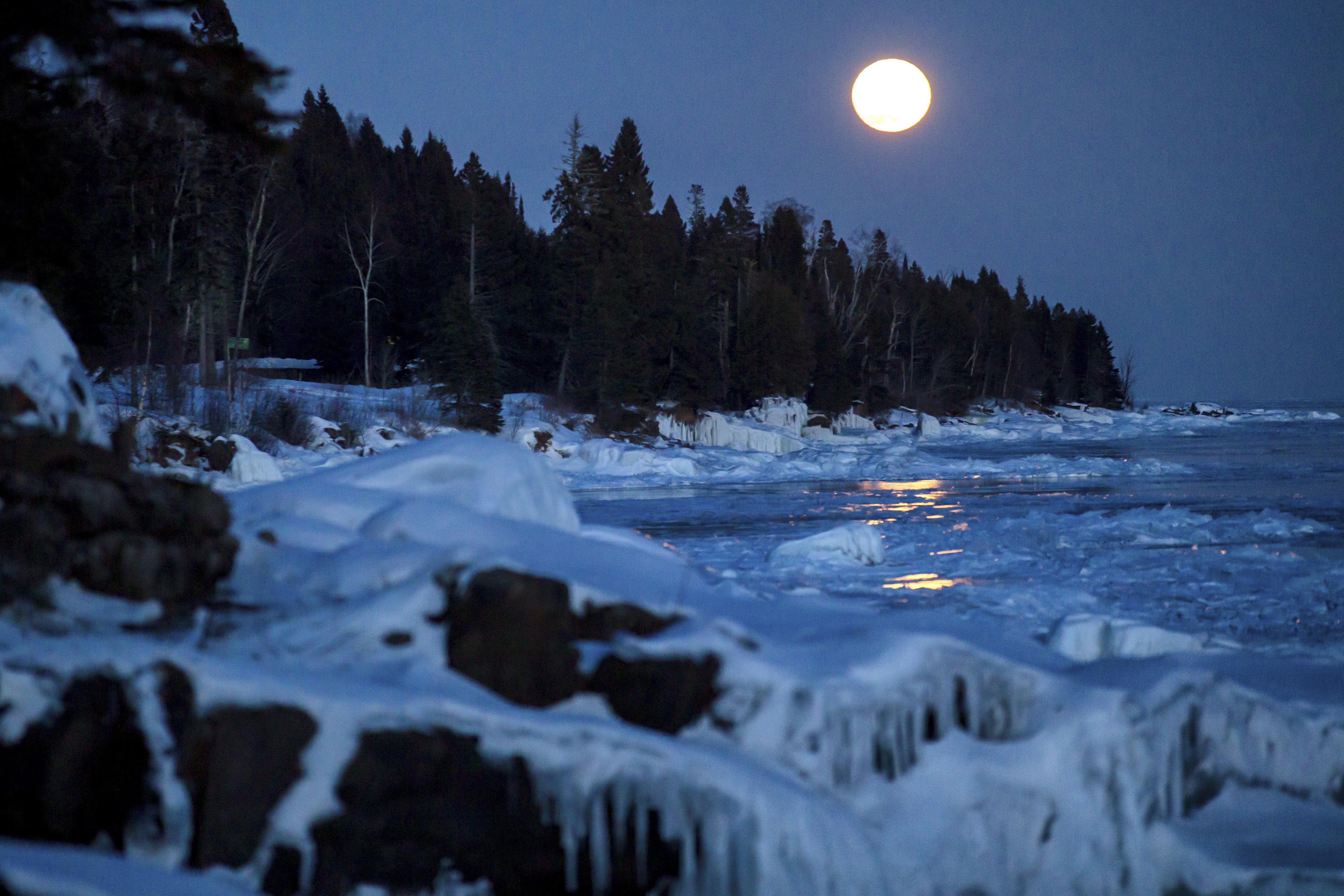 The moon rises over the ice on the shore of Lake Superior 