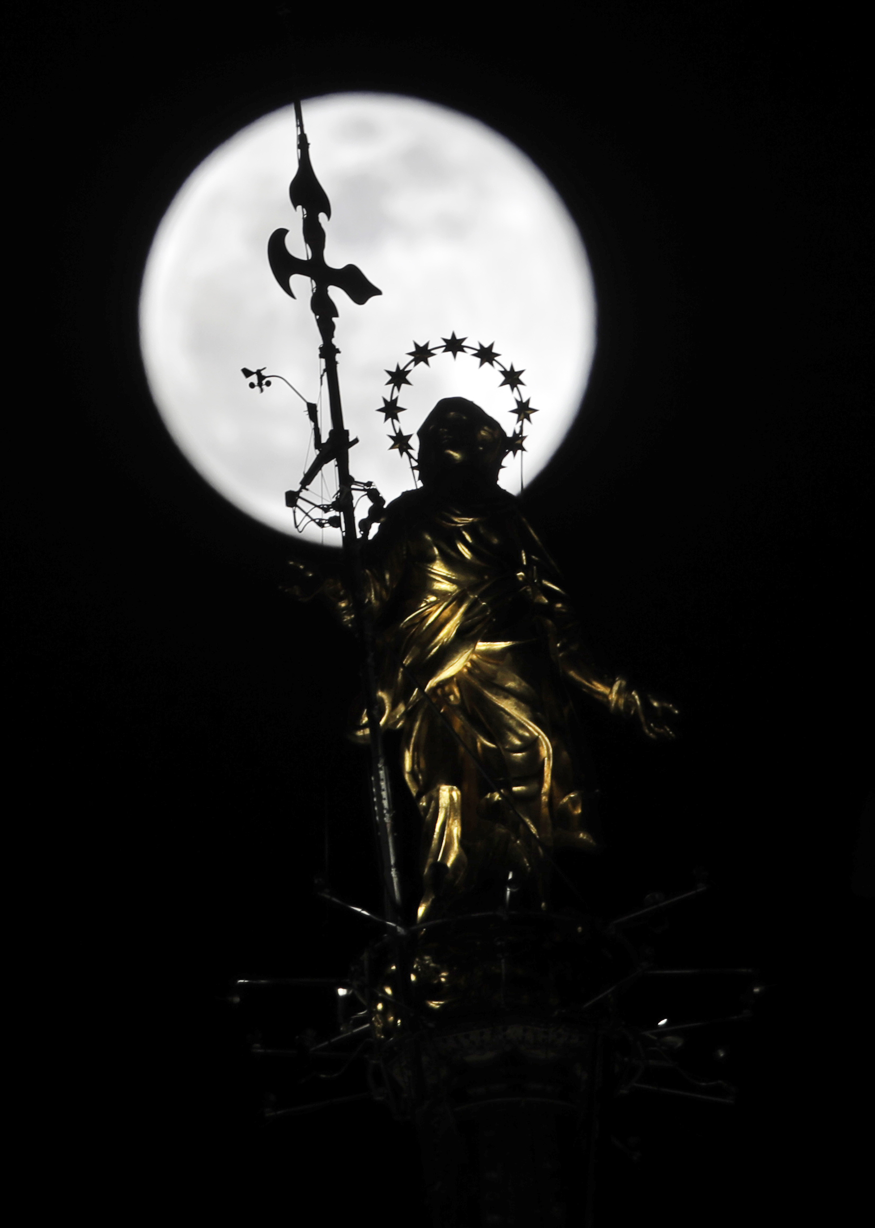 The supermoon rises behind a statue of the Virgin Mary in Milan