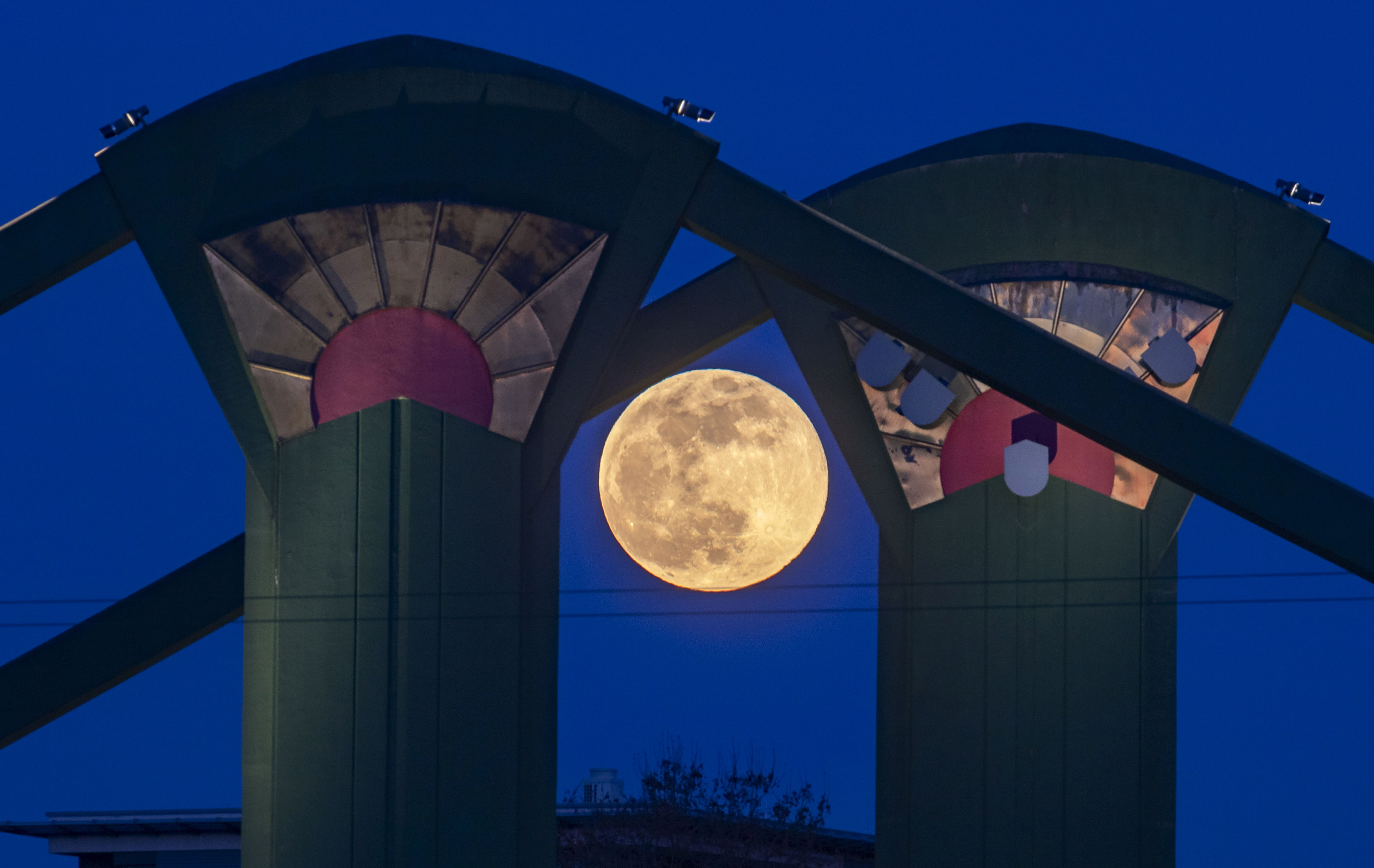 The moon is framed between illuminated concrete columns of the Floesser Bridge in Frankfurt
