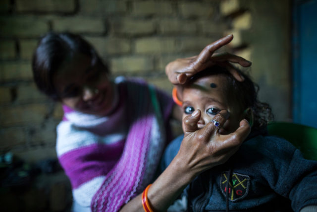 Rinku, 22, from Delhi, applies thick, black ‘kajal’ or kohl to her child Kritika’s eyes, a tradition said to ward off evil spirits in India (Water Aid/PA)