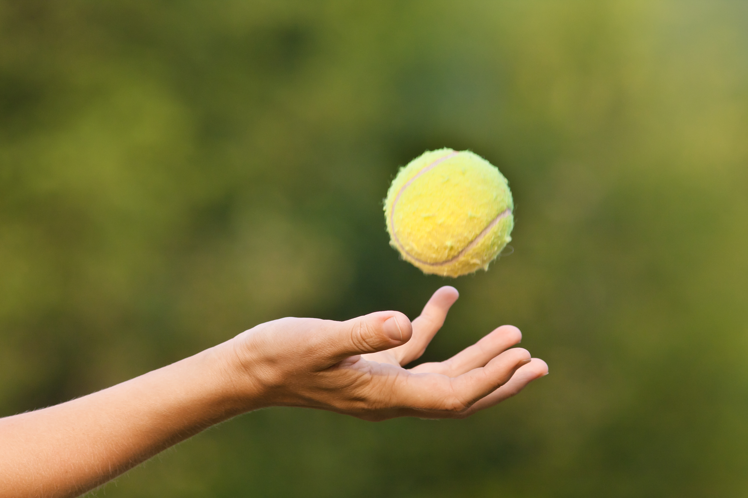 hand tossing tennis ball