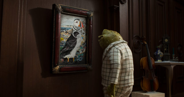 Toad hangs a memorial picture of a puffin entangled in plastic on the wall (The Wildlife Trusts/PA)