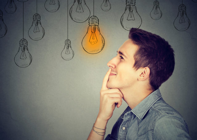 Thinking man looking up with light idea bulb above head isolated on gray wall background