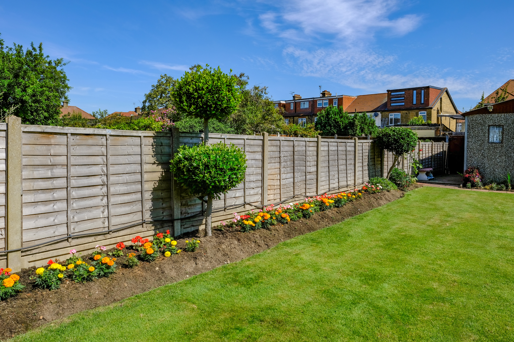 Backgarden tidy flower bed with fence and newly mown grass.