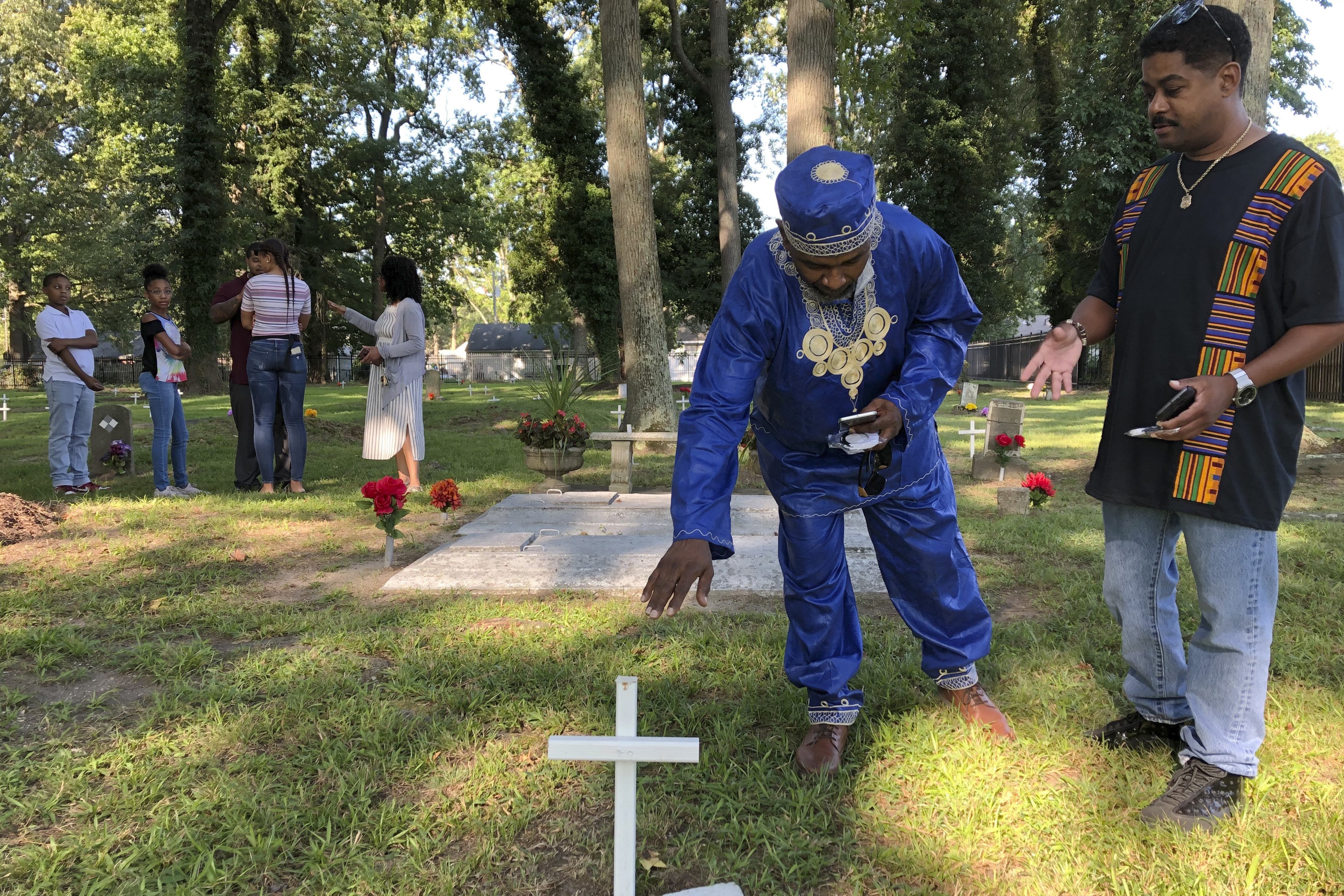 Andre Bradshaw, left, and Eric Jackson at an unmarked grave at the Tucker Family Cemetery in Hampton. They are part of a larger family that traces its roots back to the first enslaved Africans to arrive in what is now Virginia in 1619 