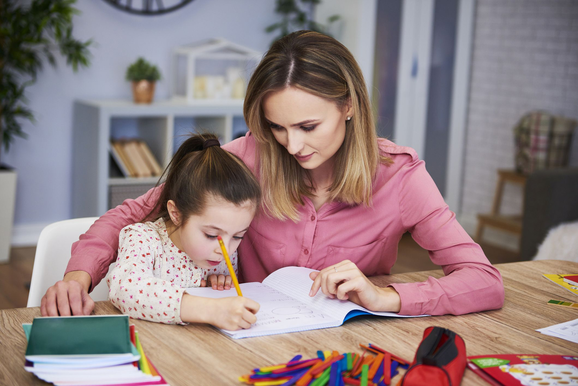 Affectionate mum helping her daughter with homework