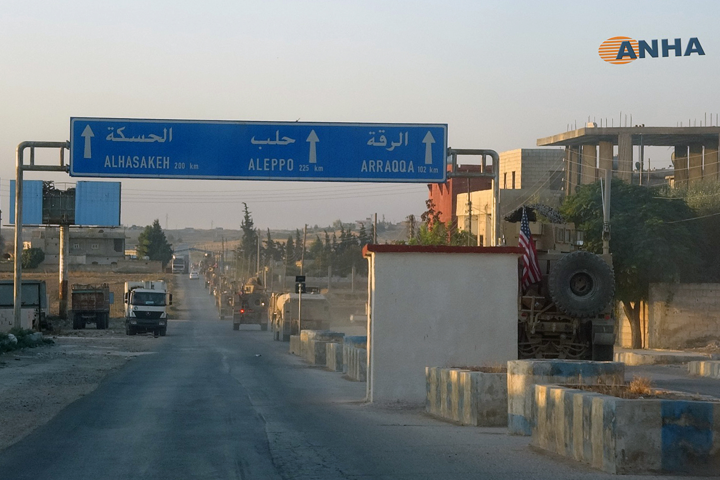 A line of US military vehicles travel down a main road in north east Syria