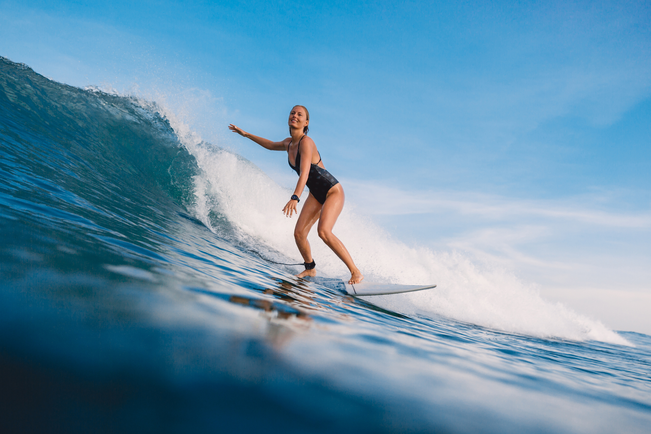Surfer woman at surfboard ride on wave. Woman in ocean during surfing.