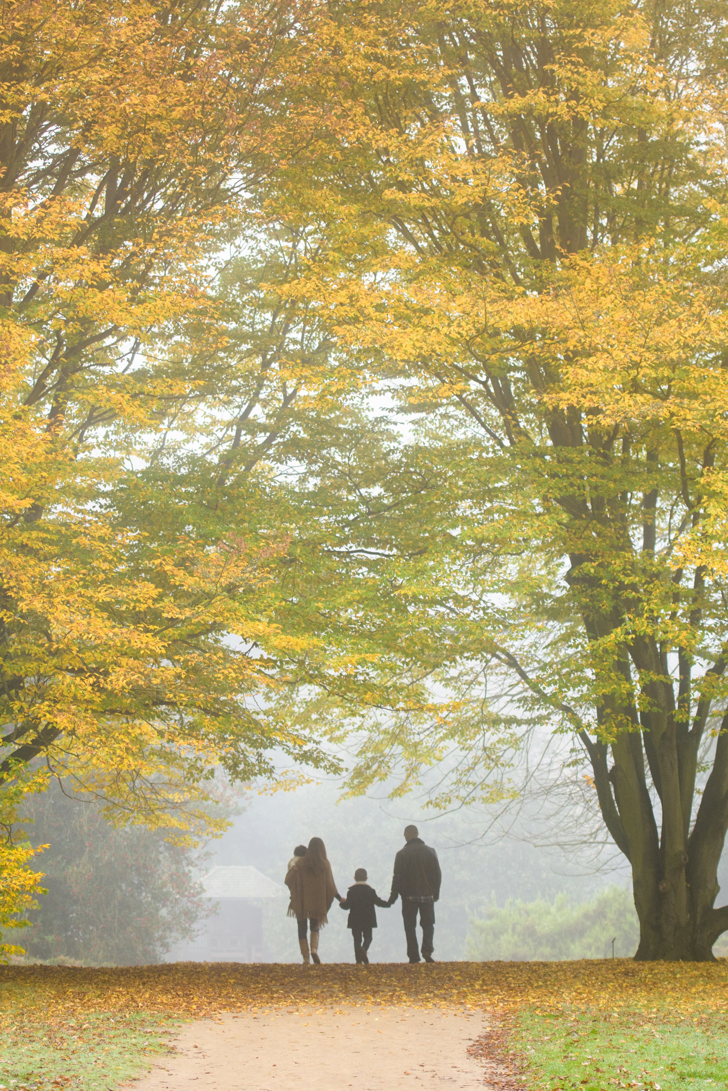 A family walks past trees in autumn colour in the Pinetum at RHS Garden Wisley (Georgi Mabee/RHS/PA)
