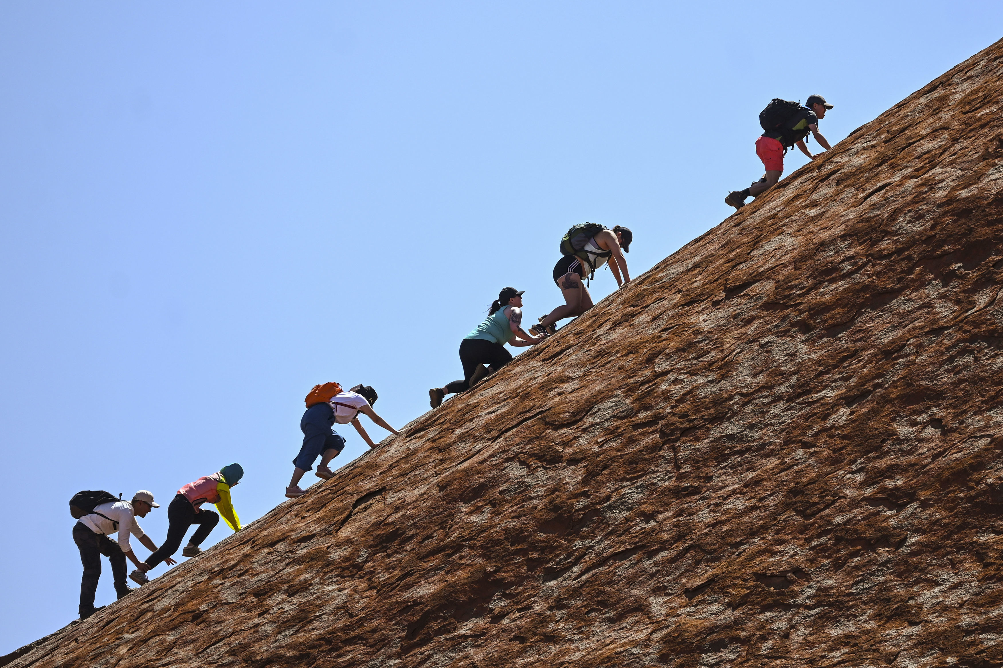 Tourists climb Uluru at Uluru-Kata Tjuta National Park