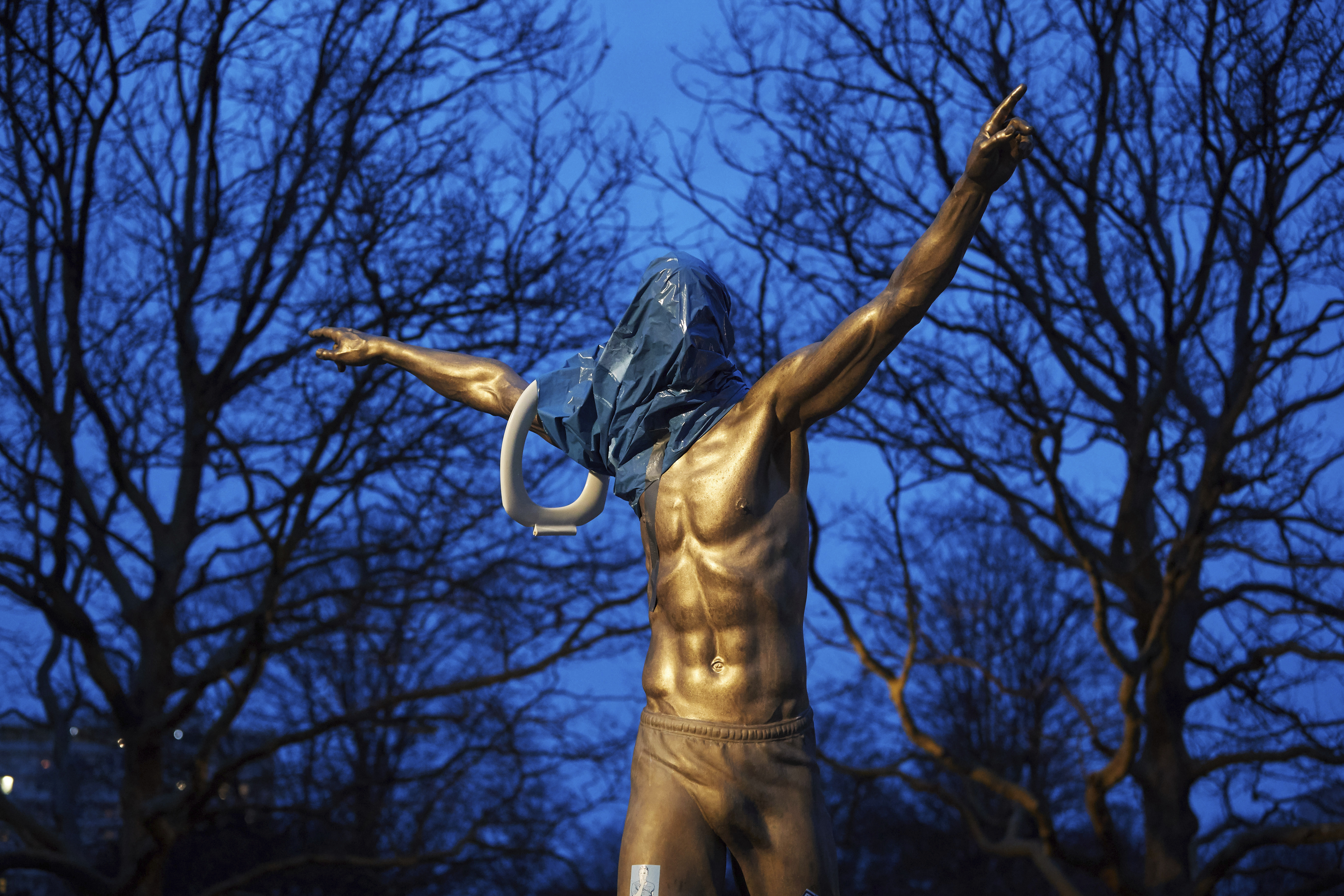 A blue plastic bag and a toilet seat hangs from the statue of Zlatan Ibrahimovic in Malmo