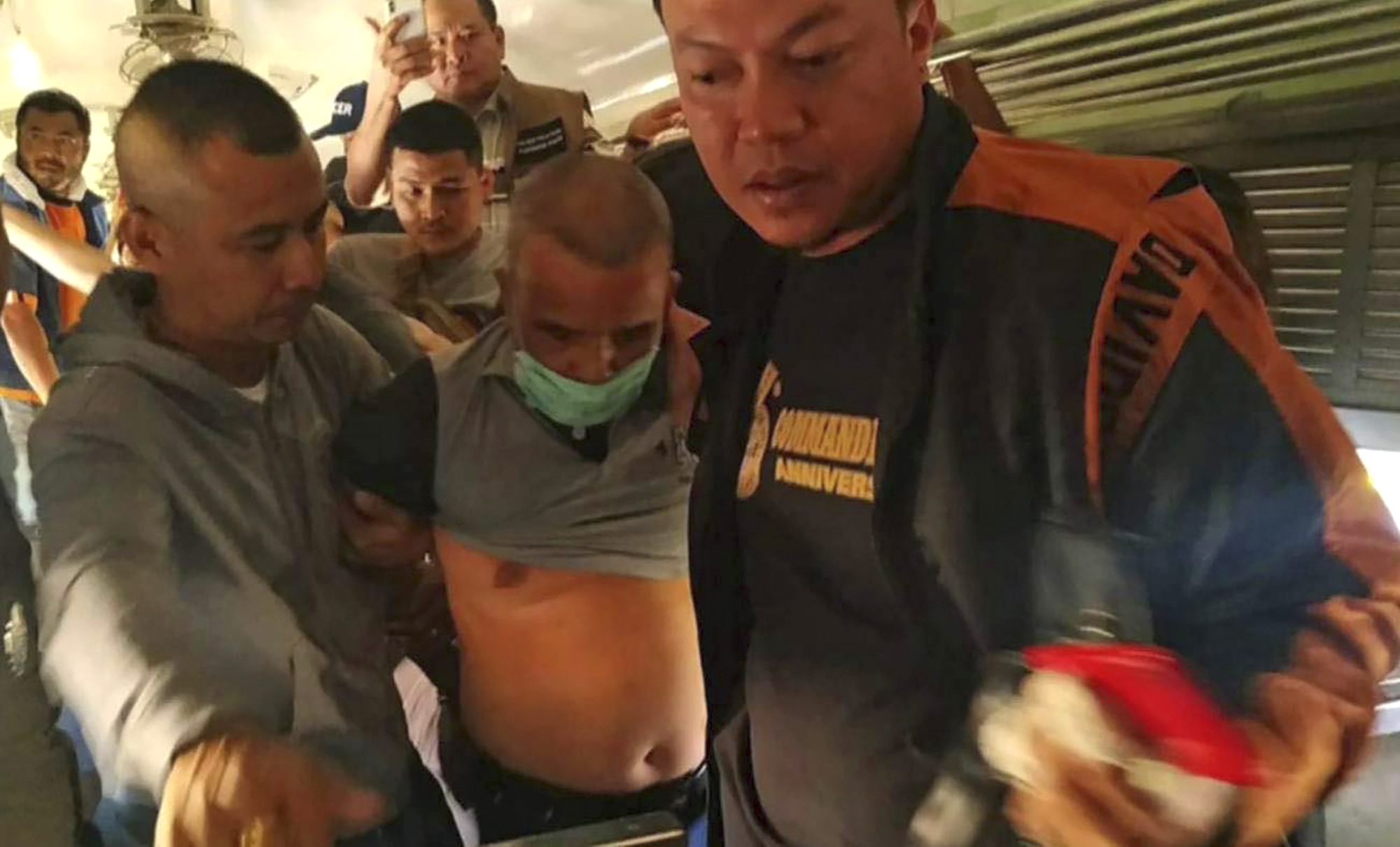 Thai police officers escort Somkid Poompuang, centre, after his arrest at the Pak Chong train station