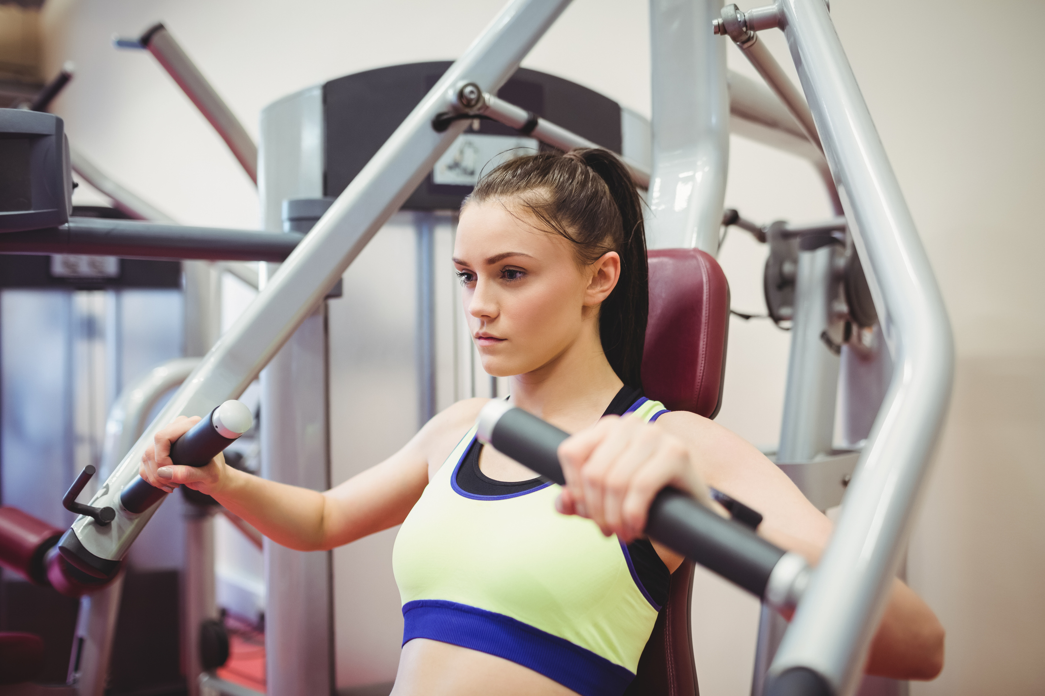 Fit woman using weights machine for arms