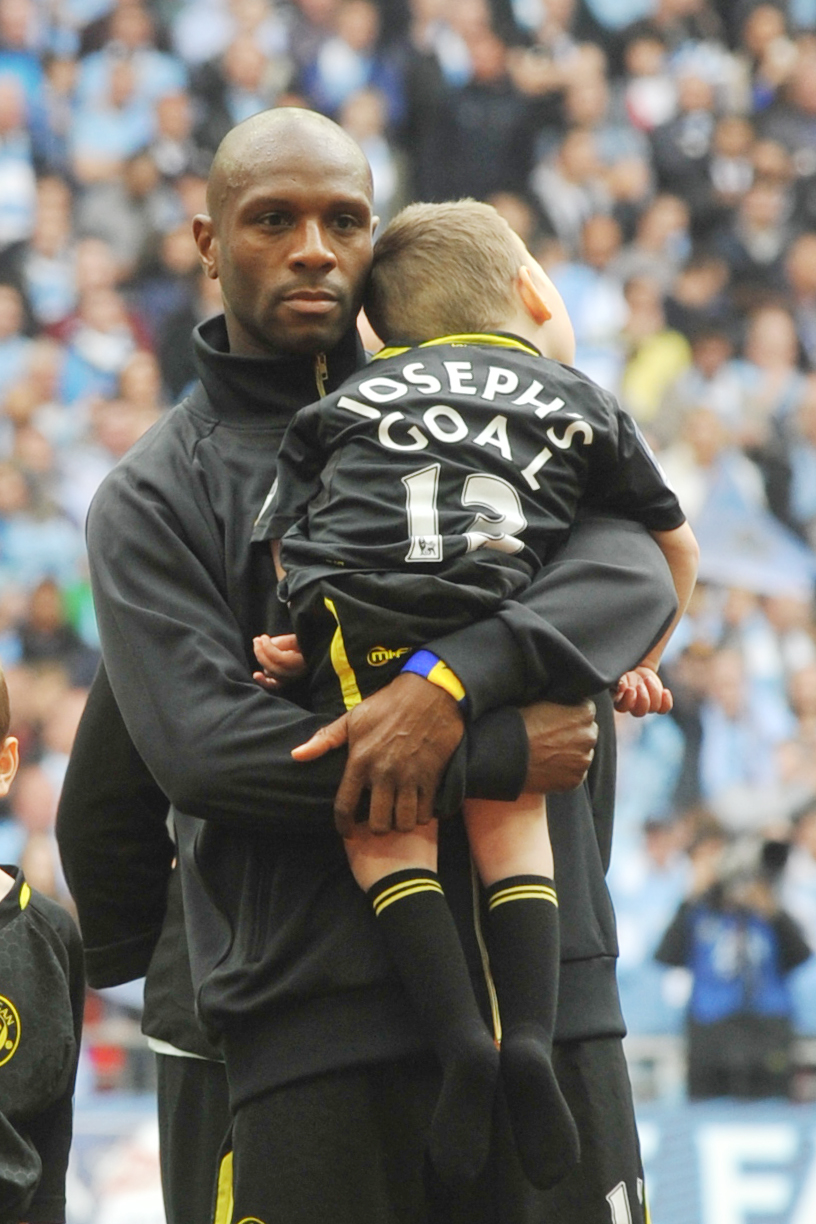 Joe Kendrick is carried onto the Wembley pitch by Wigan captain Emmerson Boyce at the 2013 FA Cup final