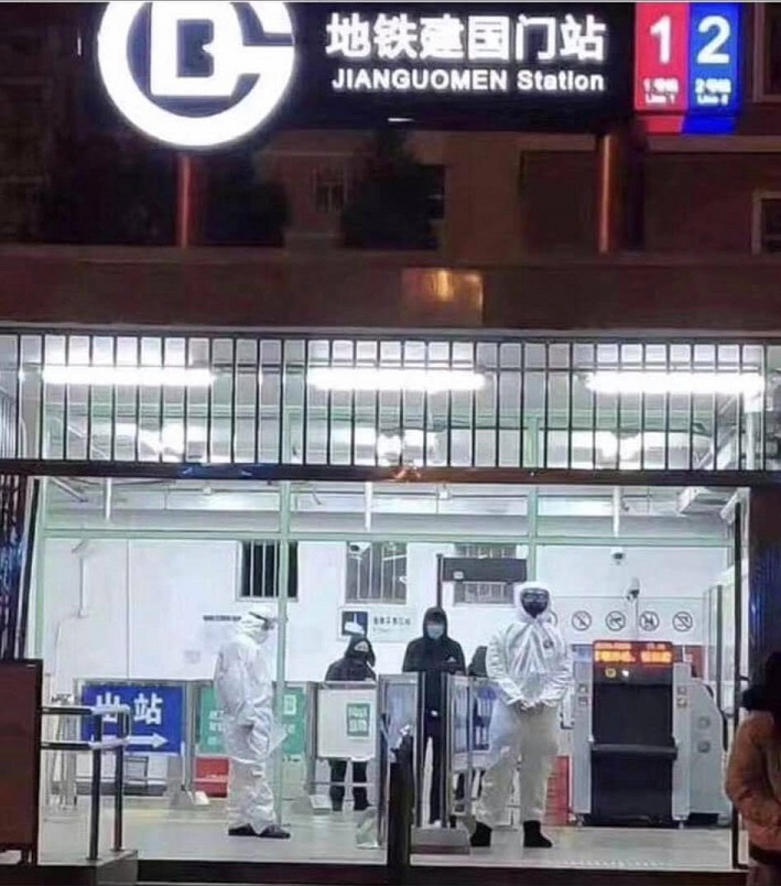 People wear full body suits and masks at a Subway station in Beijing