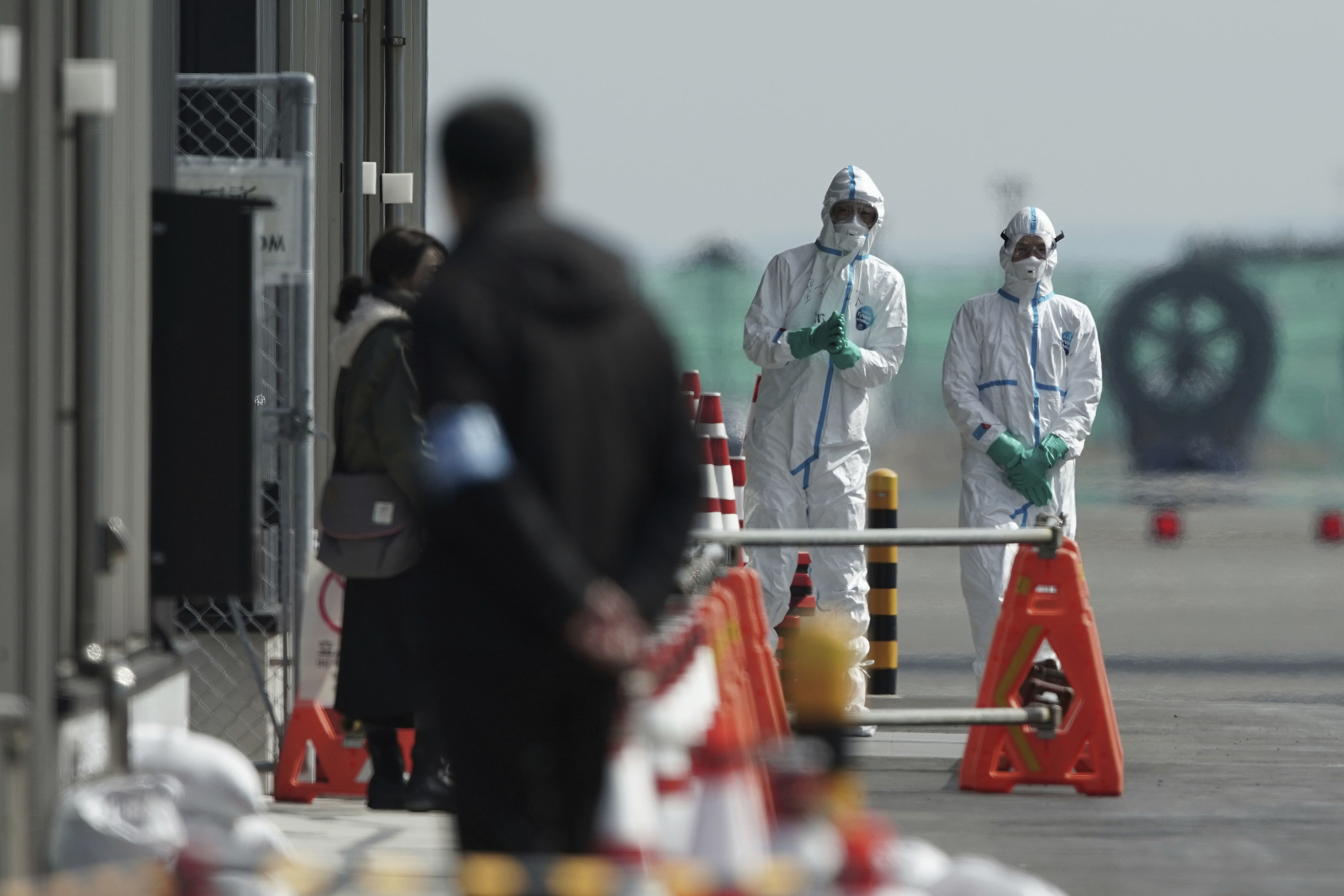 Officials in protective suits talk