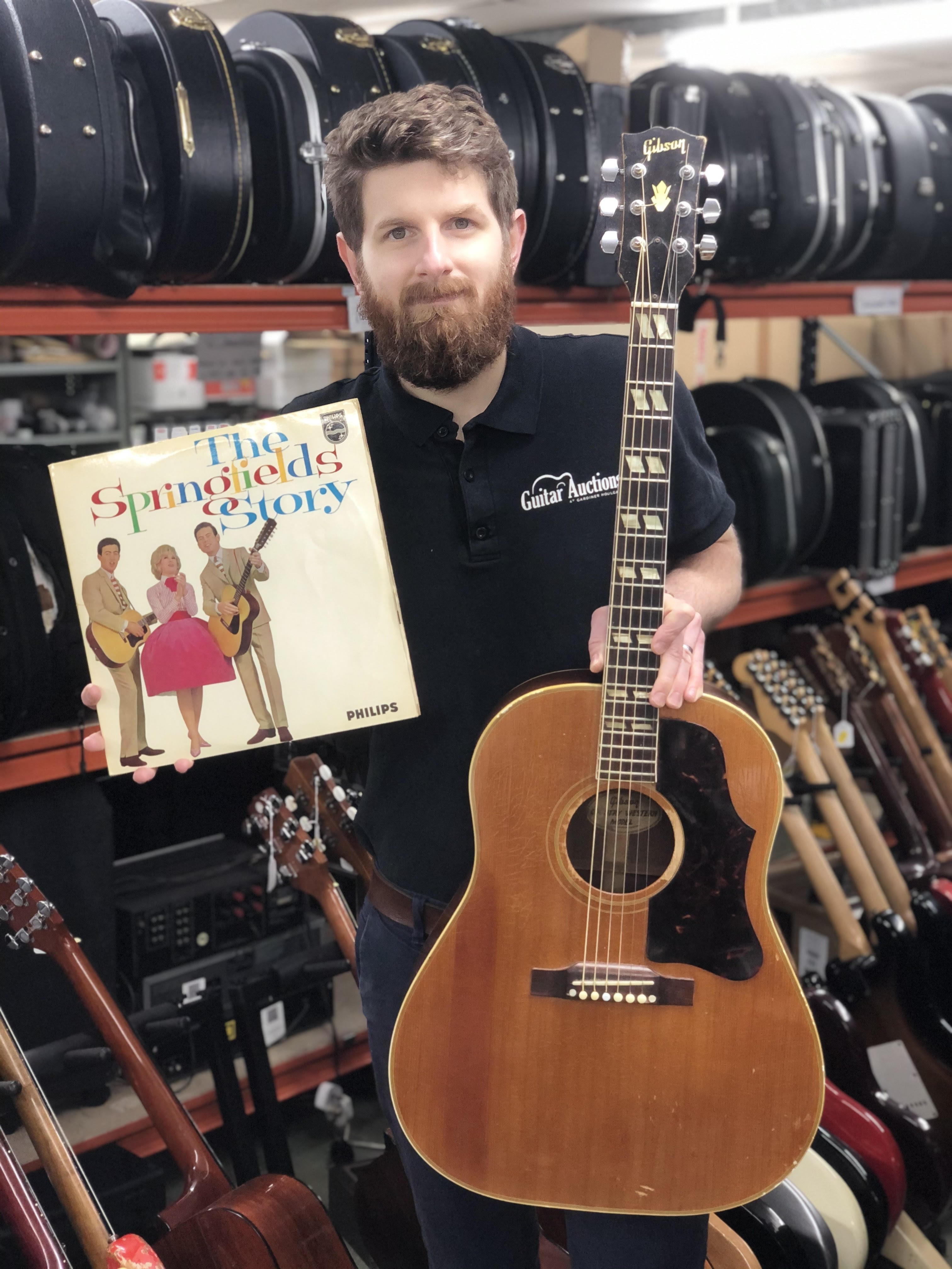 Auctioneer Luke Hobbs with Mike Hurst's famous guitar (Gardiner Houlgate/PA).