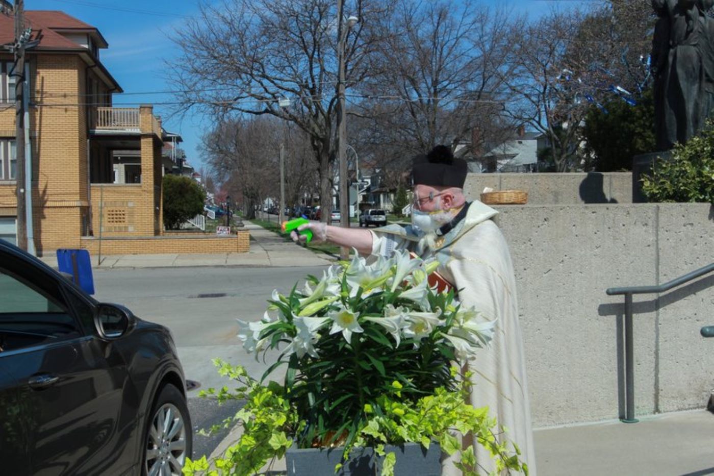 Father Pelc squirts holy water towards a car (Natalie White/AP)