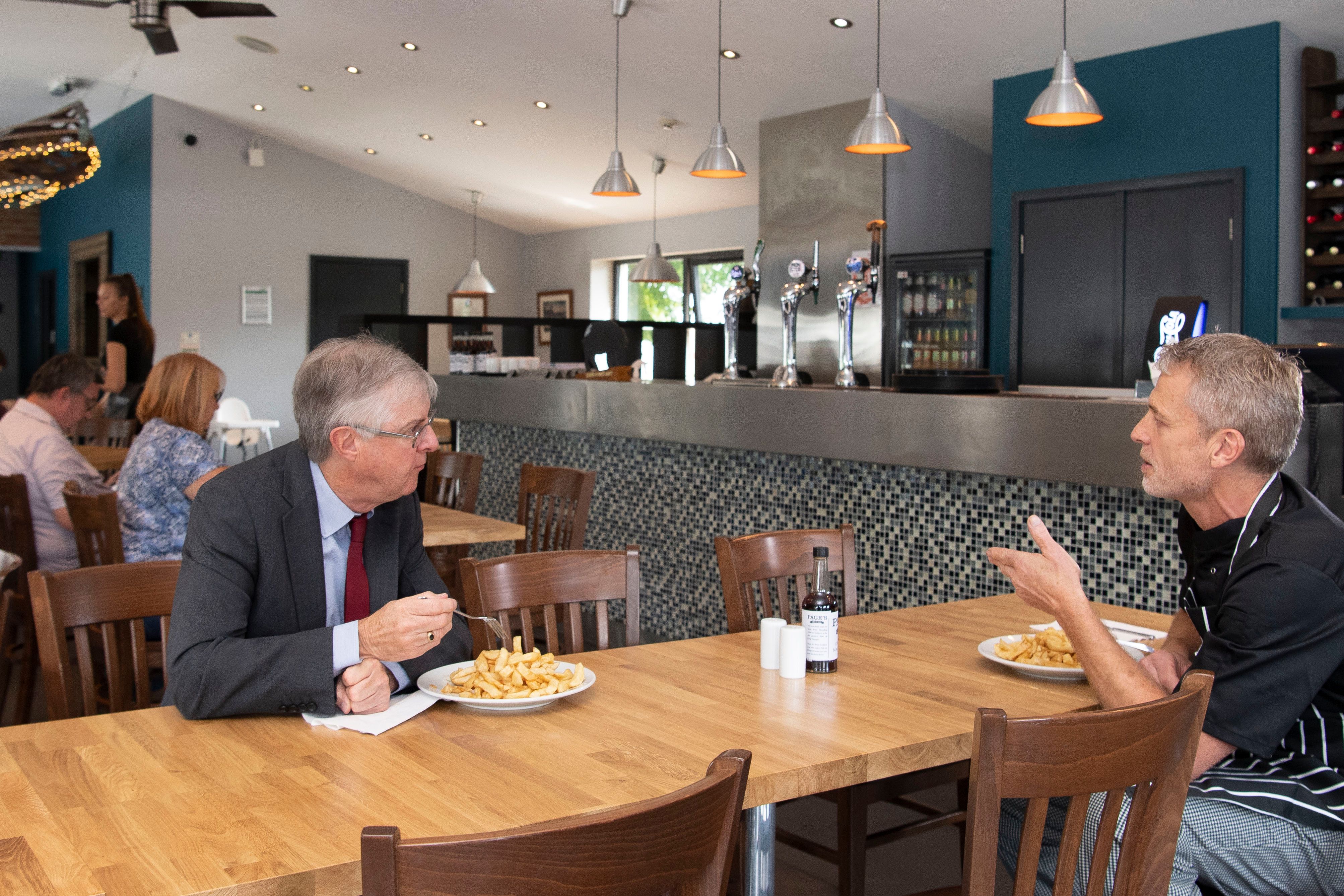 First Minister Mark Drakeford speaks to the owner of Page's Fish and Chips restaurant, John Page