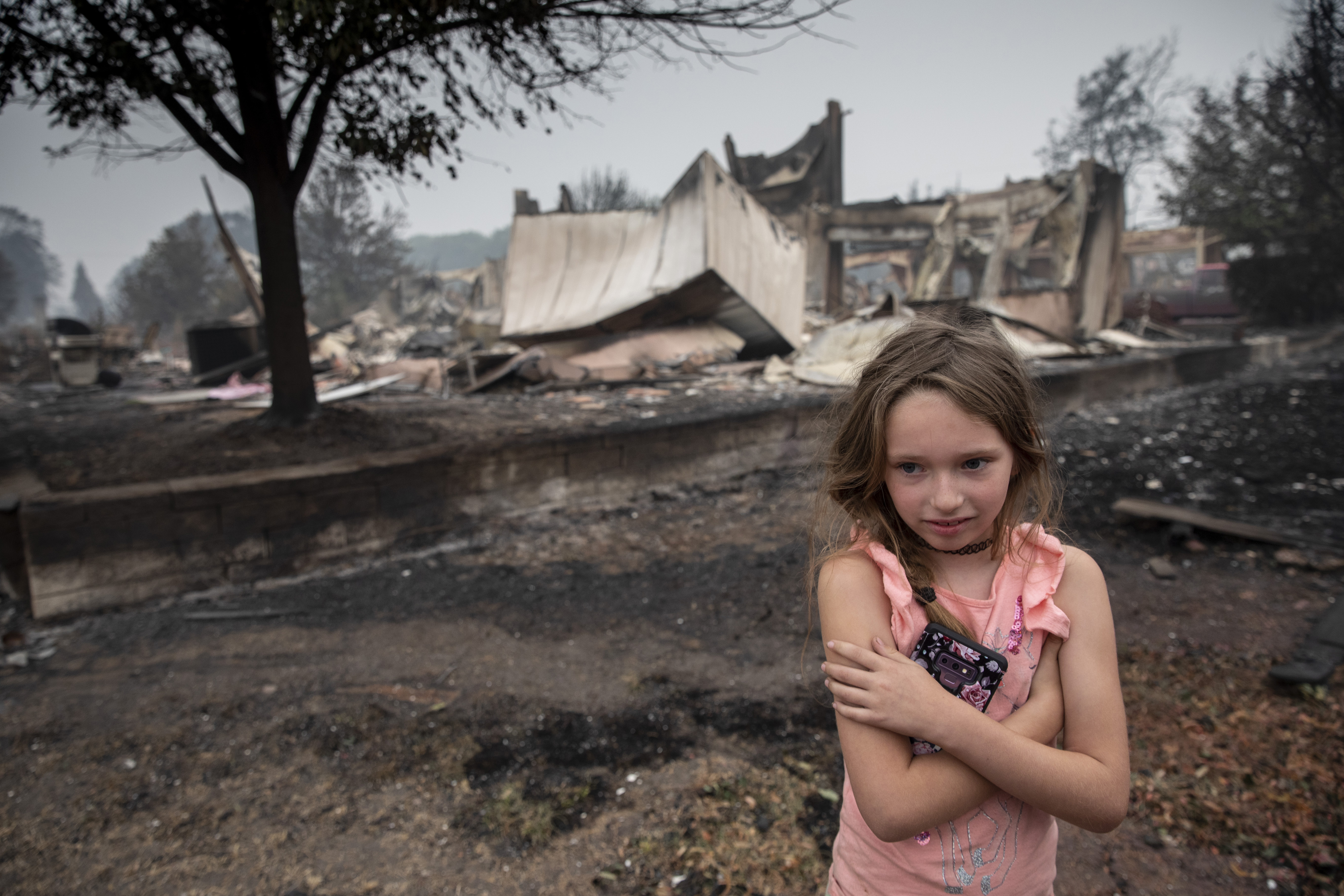 A girl in front of fire-hit buildings
