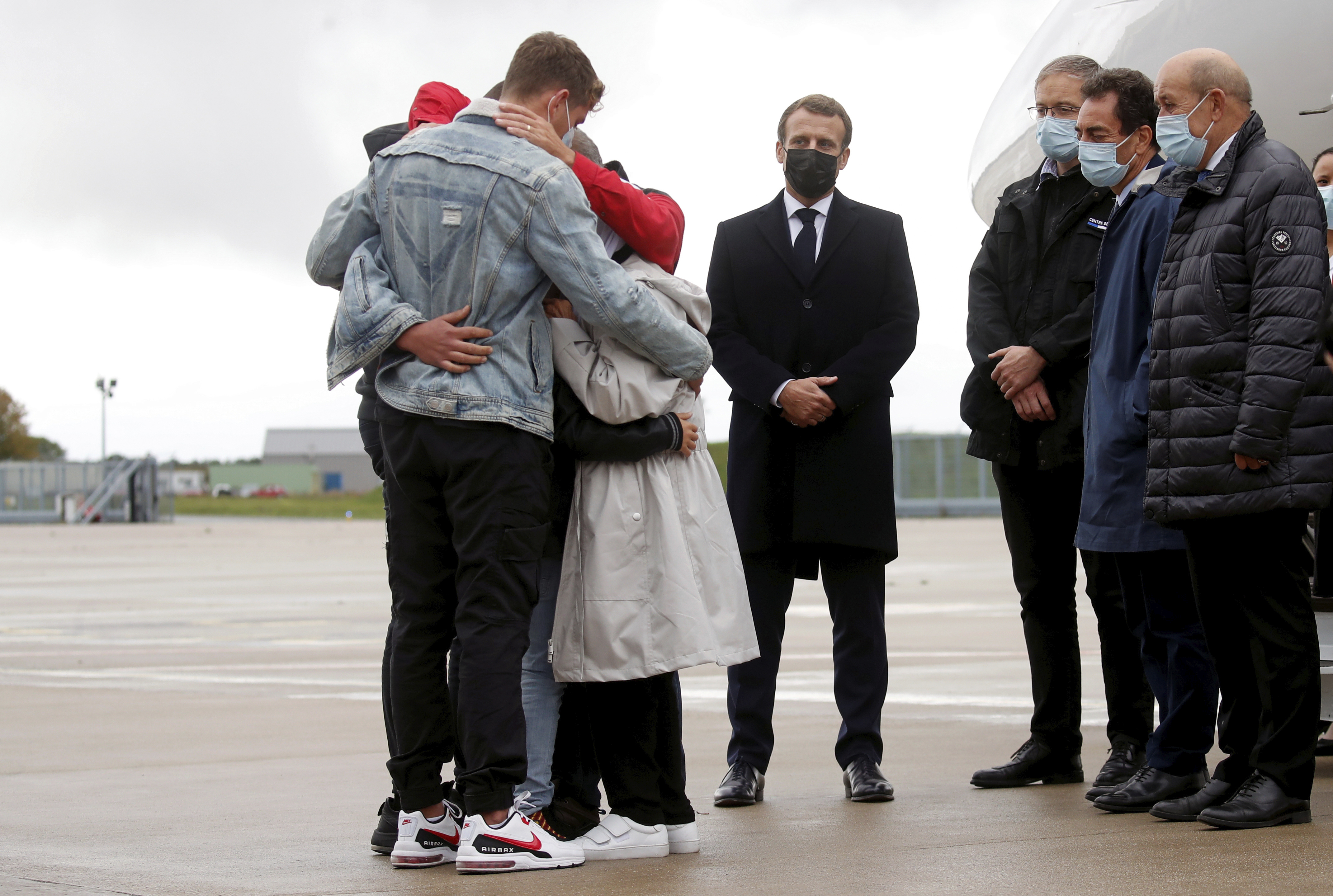 Emmanuel Macron stands as Sophie Petronin is greeted by relatives