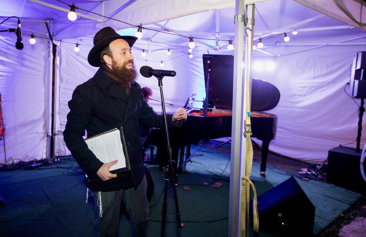 Rabbi Mendy Korer talking on stage at a previous Islington menorah lighting