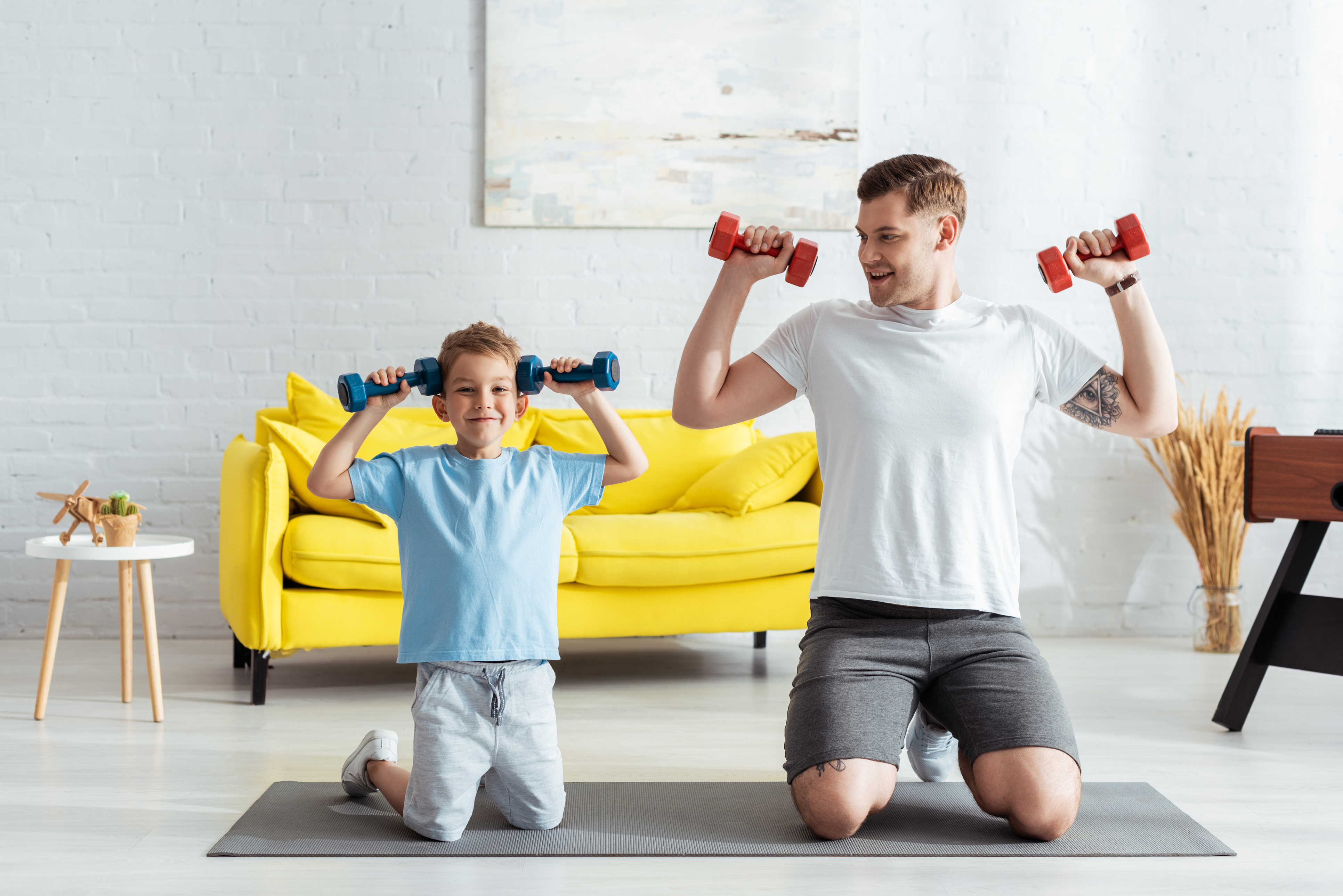 Dad and child lifting weights inside