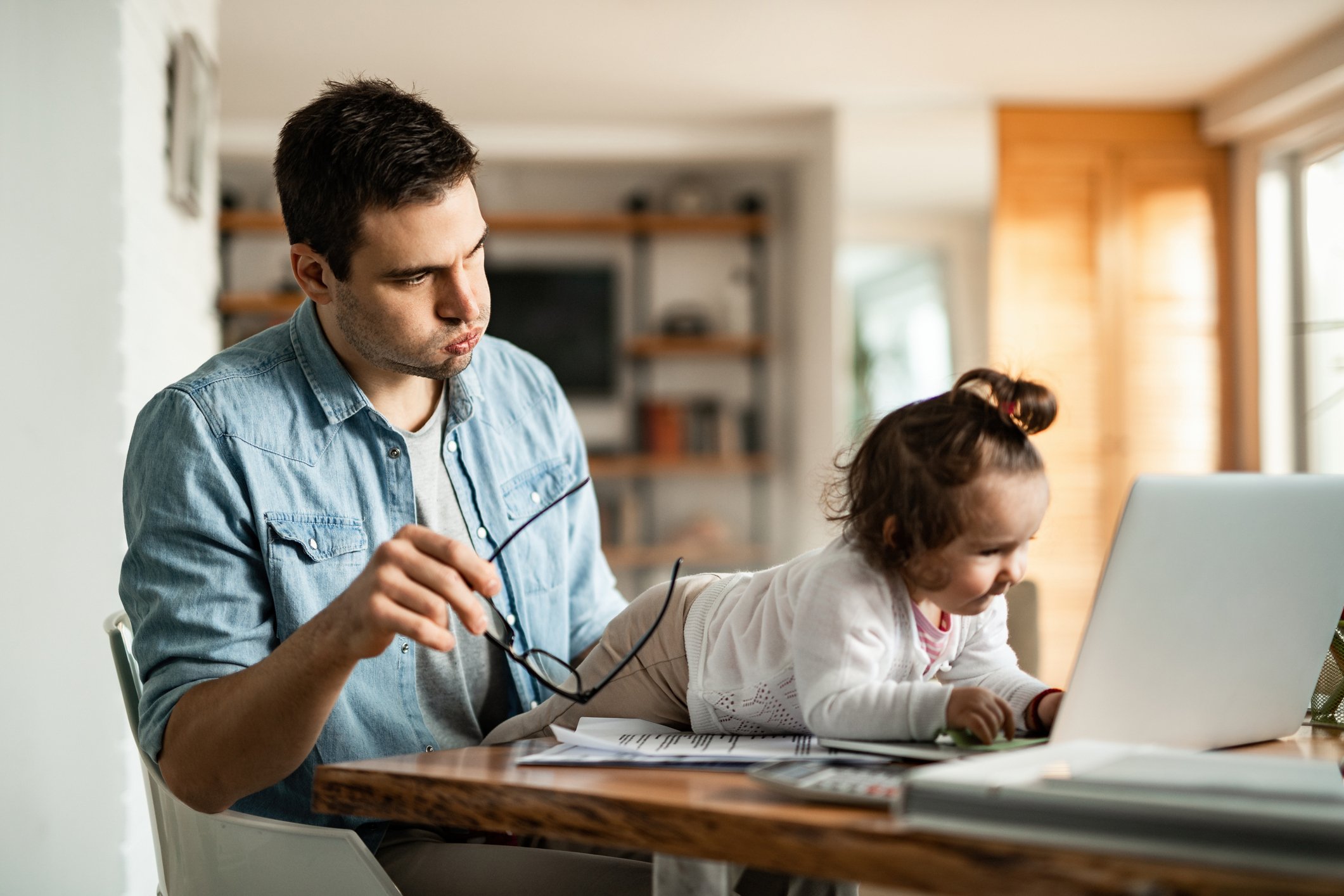 man trying to work while toddler plays on the table