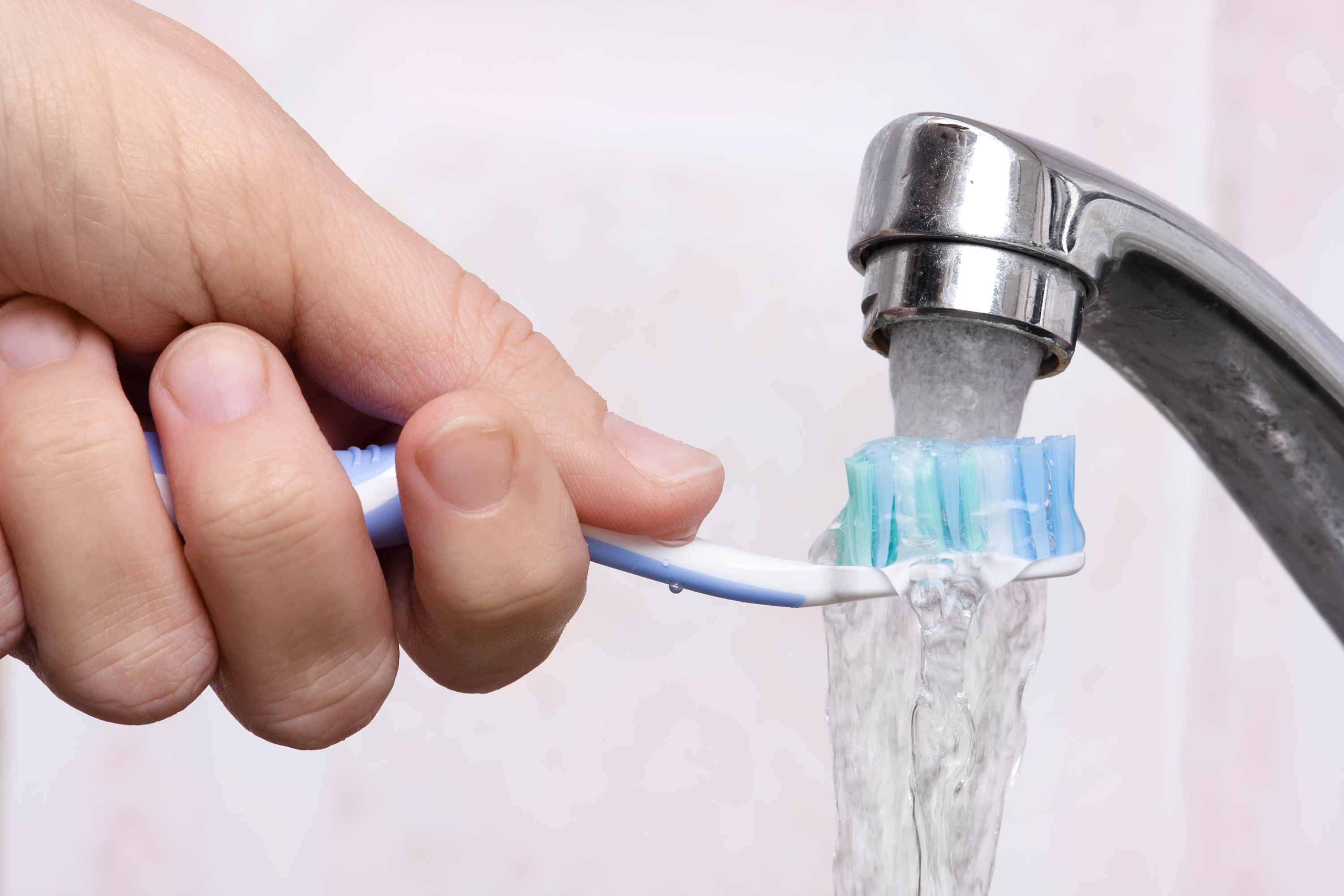 hand washing toothbrush under running water