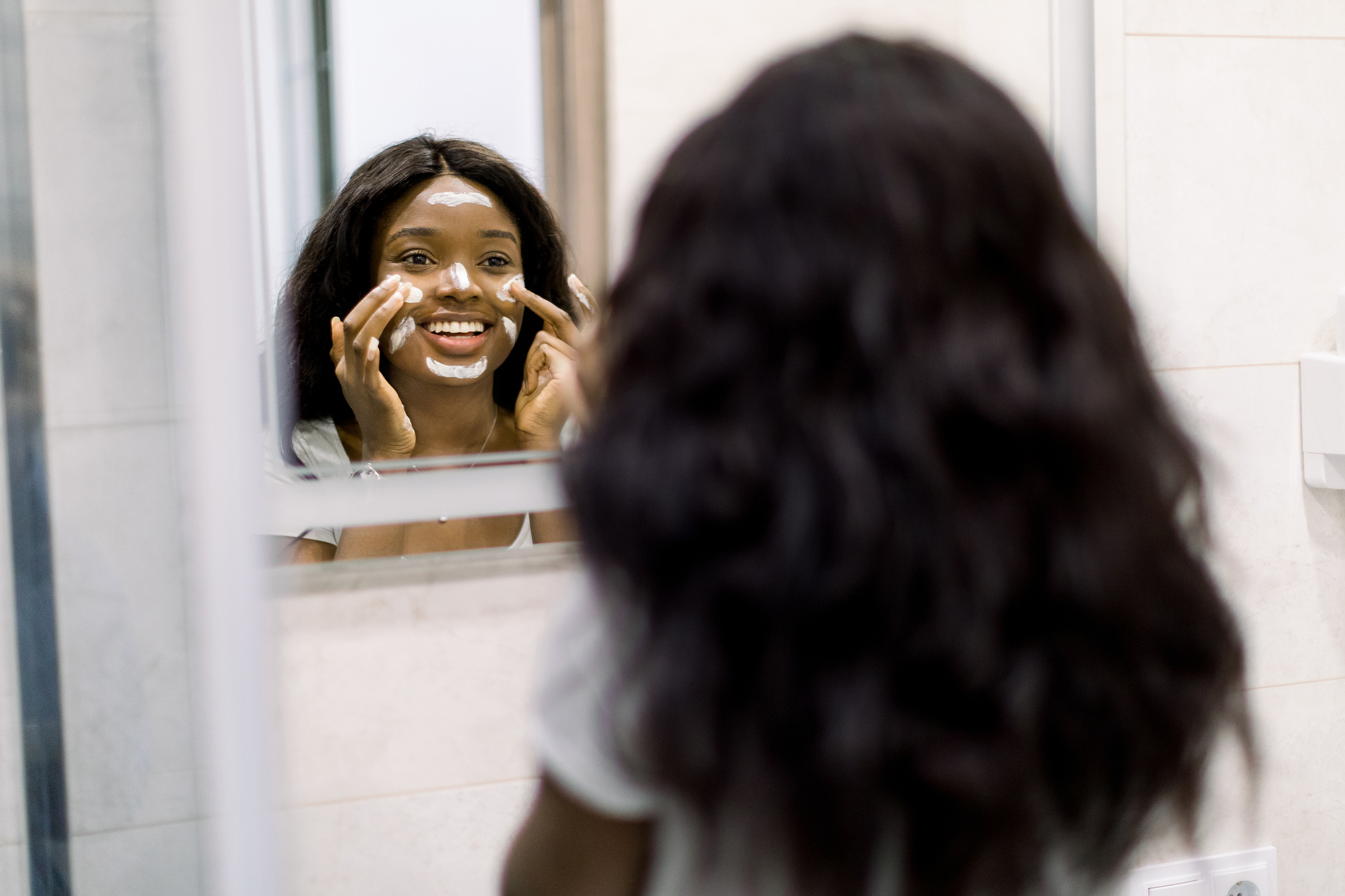woman applying beauty products looking in the mirror