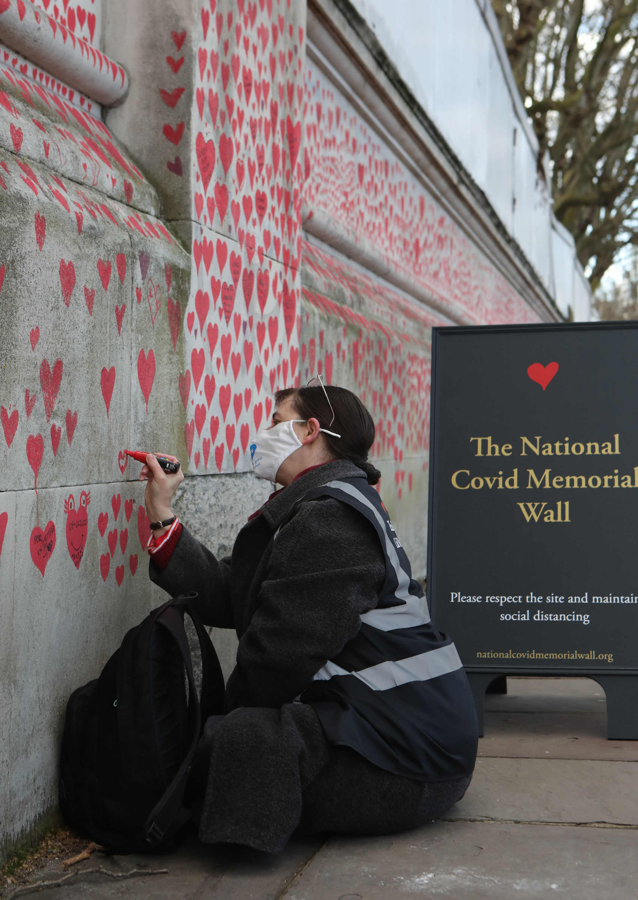A volunteer adds hearts to the National Covid Memorial Wall in Westminster, central London