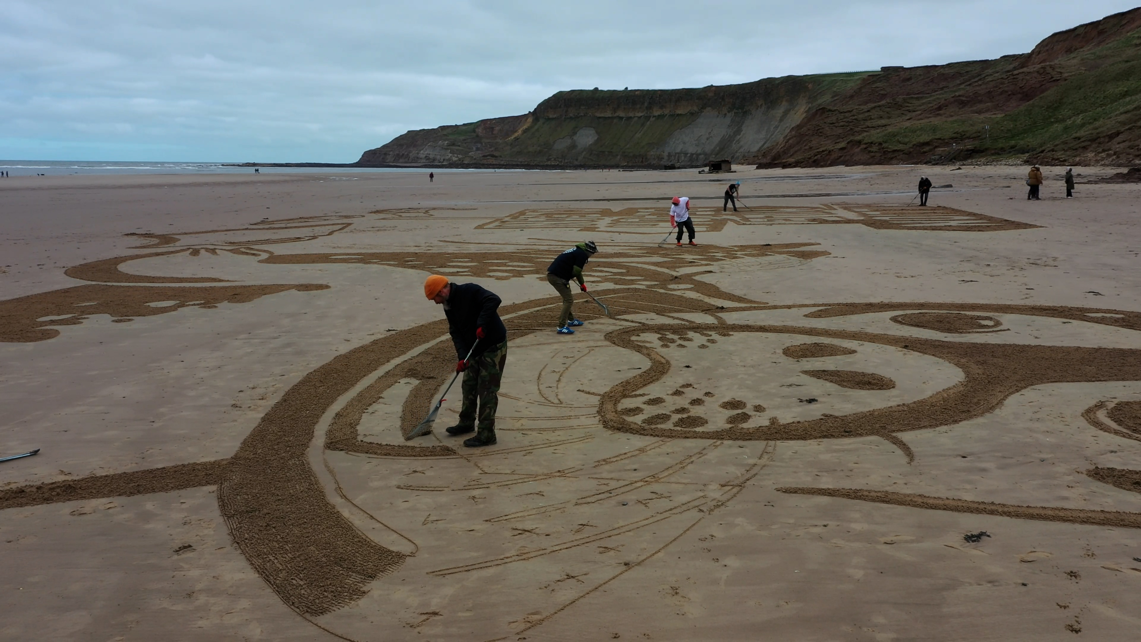 The sand drawing being created on Cayton Bay in Scarborough (Surfers Against Sewage/PA)