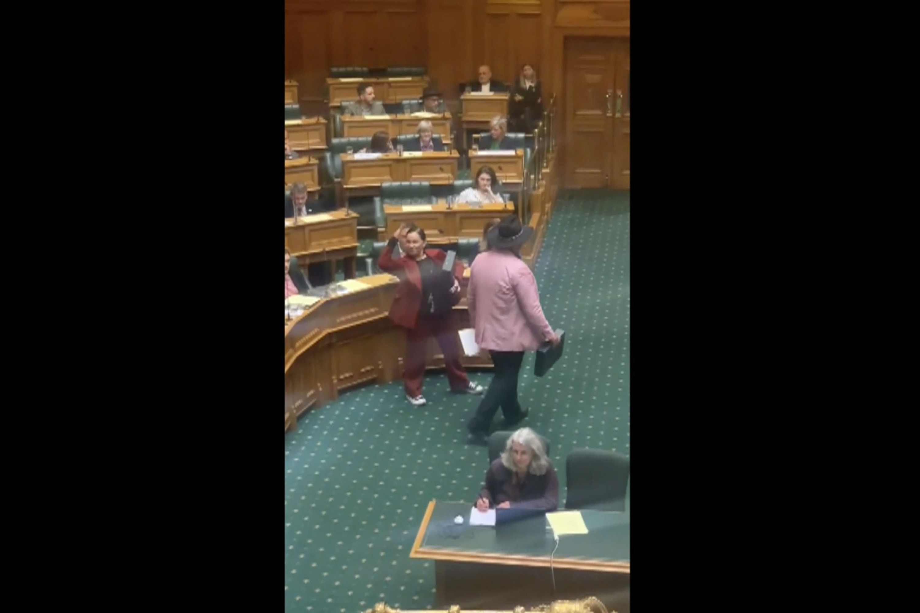 Rawiri Waititi, right, leaves parliament's debating chamber after performing a Maori haka in Wellington, New Zealand