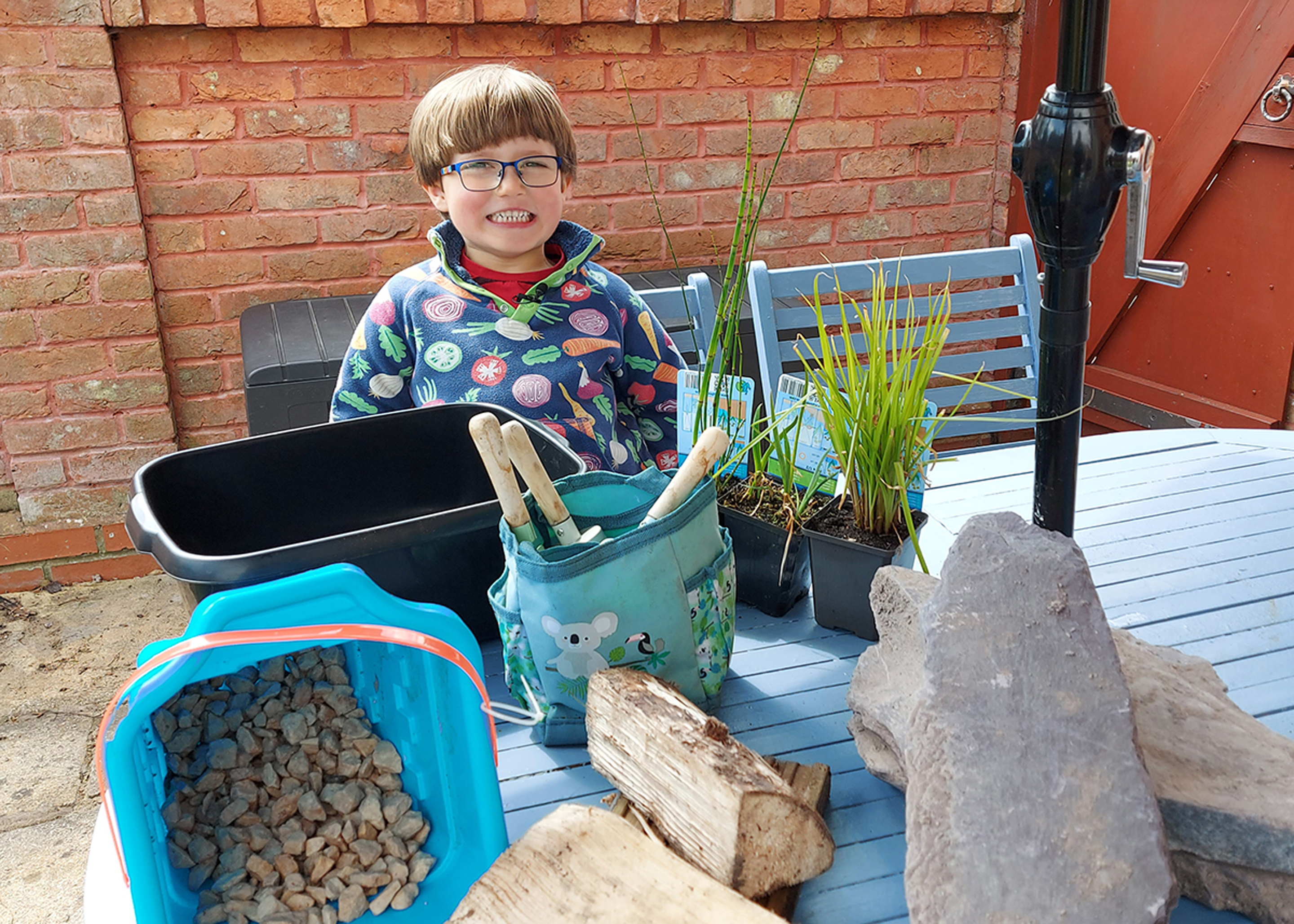 A boy with some of the materials you''ll need to make a mini pond (Garden Organic/PA)